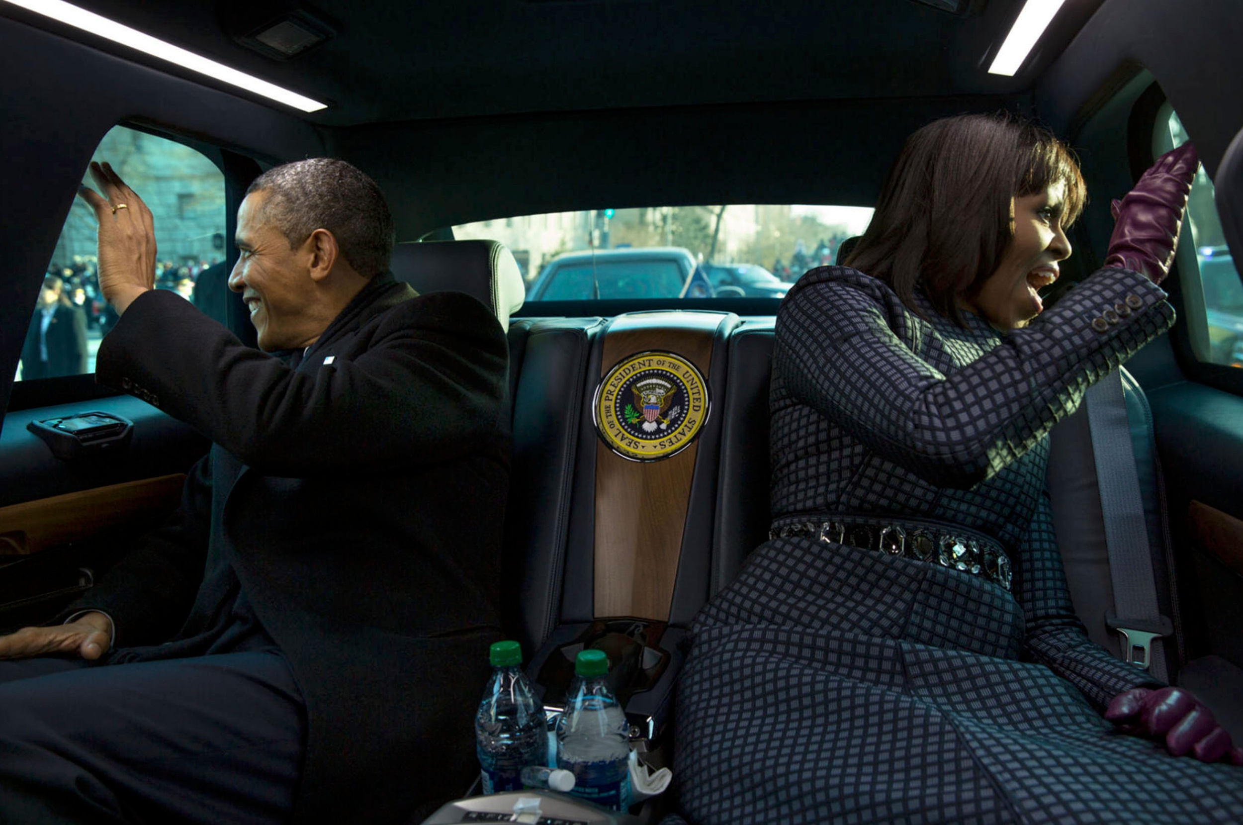 President Barack Obama and First Lady Michelle Obama waving out of car windows