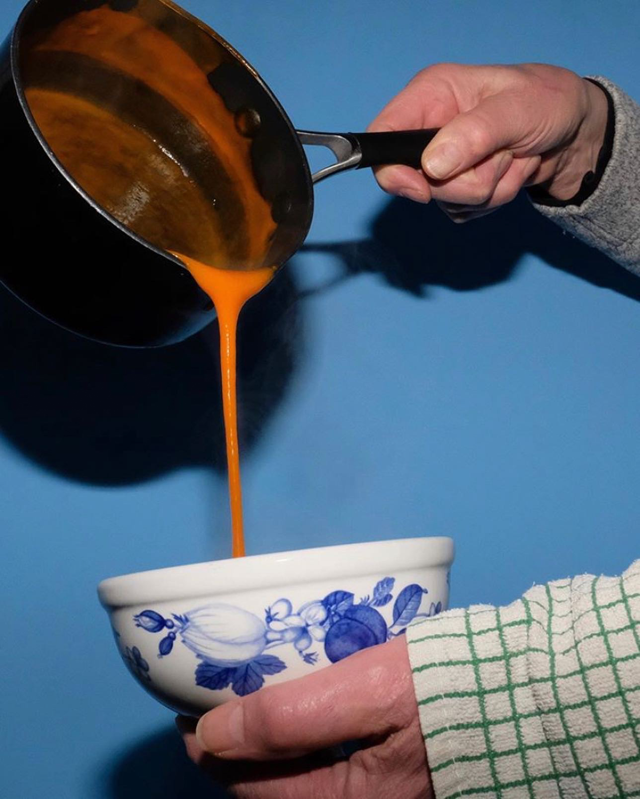 tomato soup being poured into a bowl