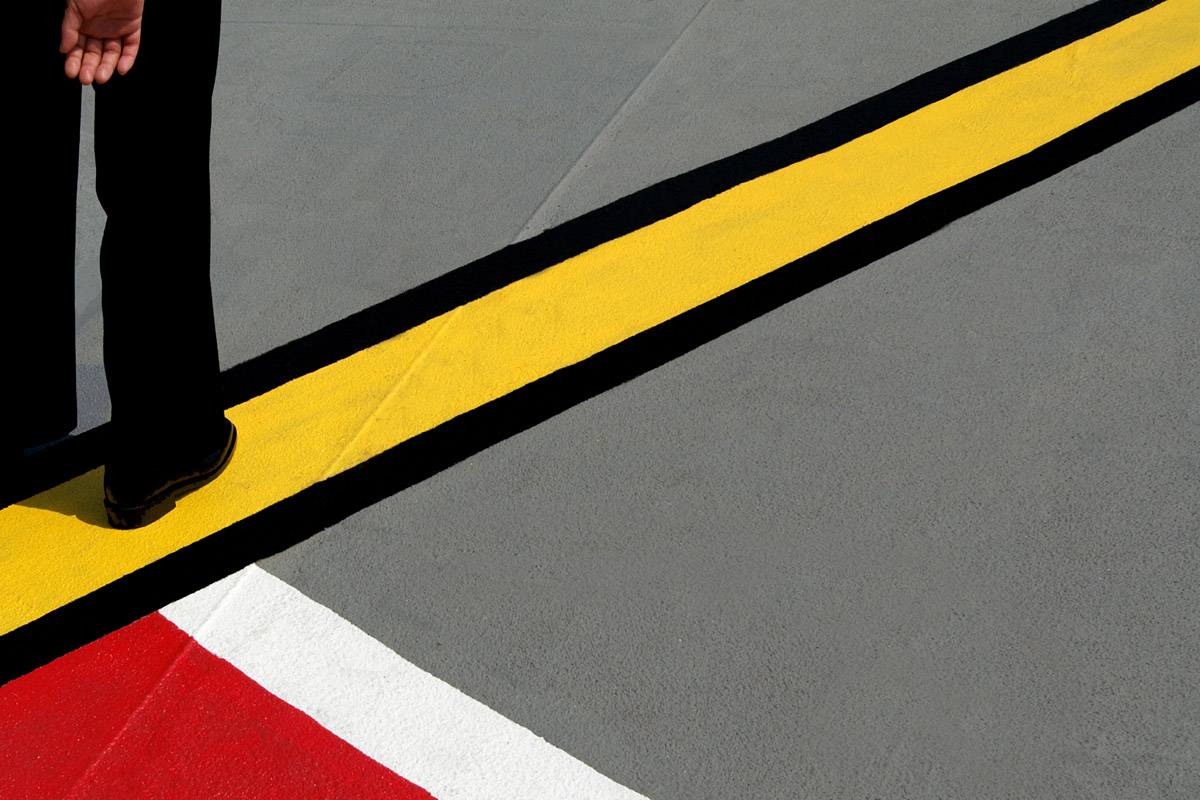 A person stands on a bright yellow line with a thick black outline on the street