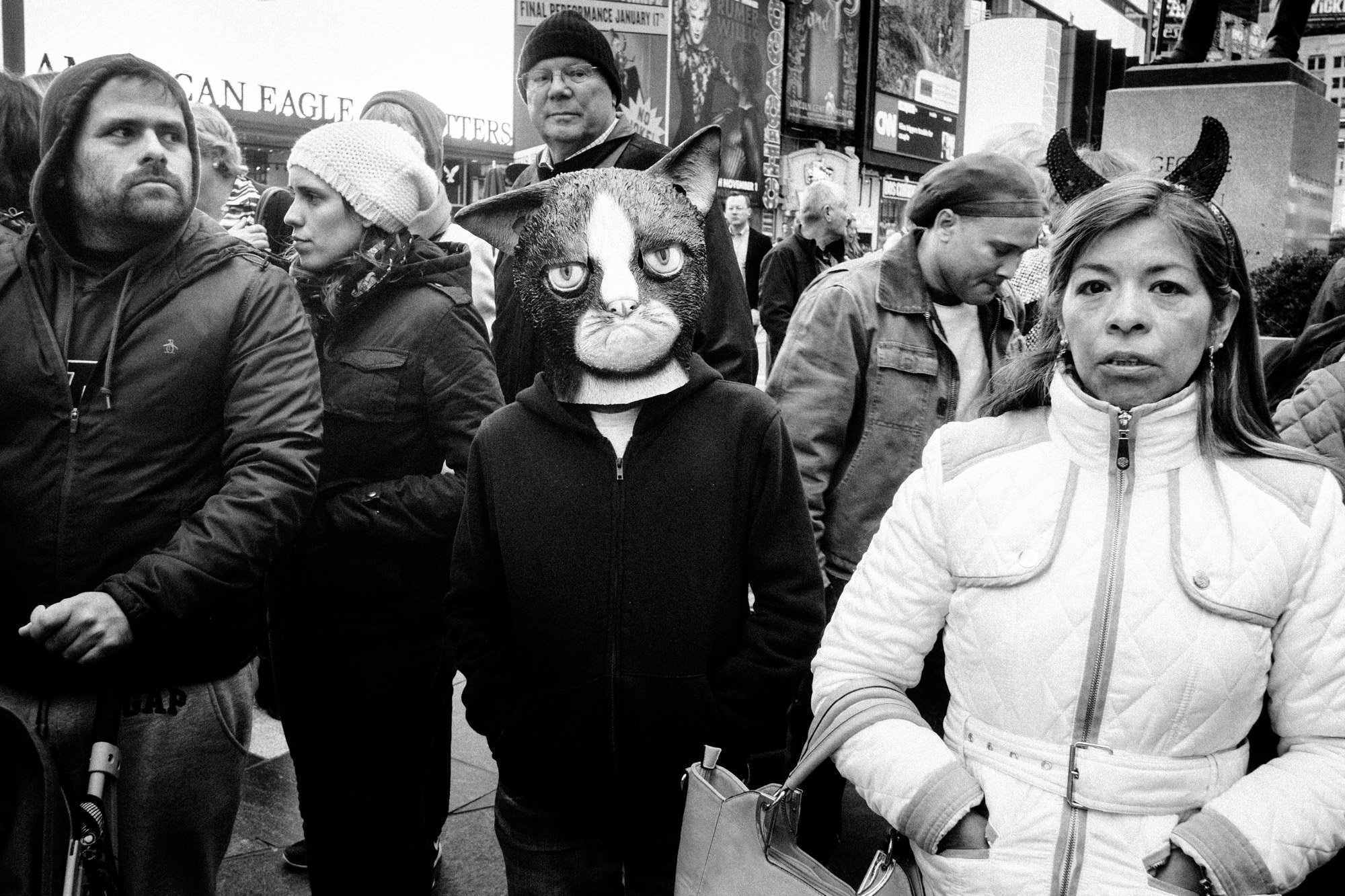Straatfoto van veel mensen met een persoon in het midden van het frame die een raar katten masker draagt, gefotografeerd door Gulnara Samoilova