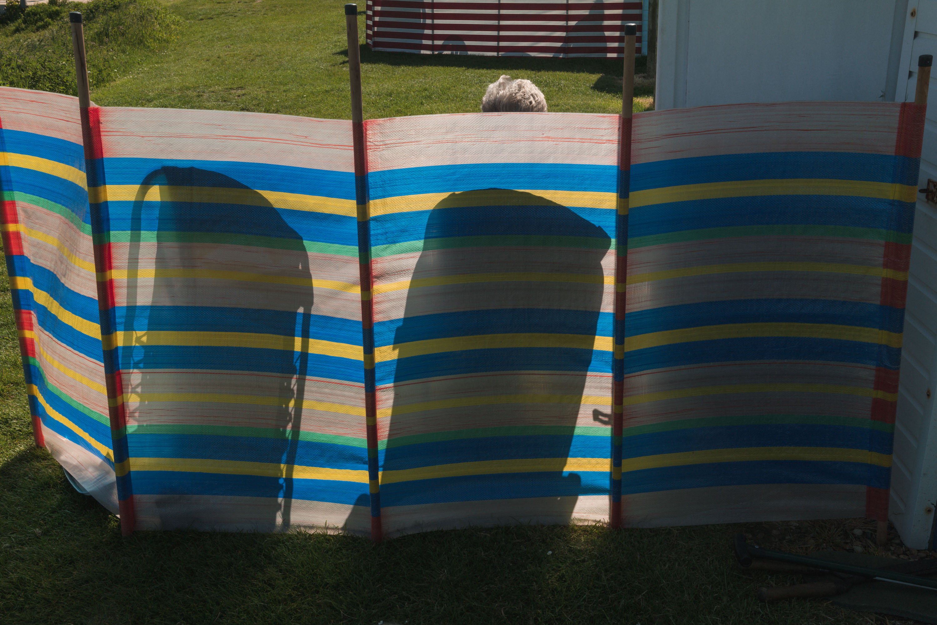 Two chair silhouettes on a striped wind-guard, by Ian Howorth with Leica SL2 and Sigma 35mm f/1.2 DG DN ART