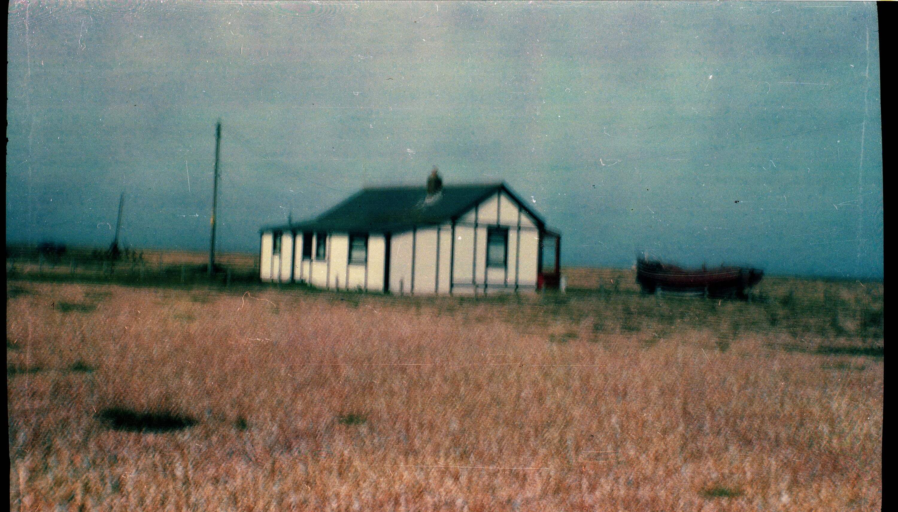 very old looking film photo of a house by the sea in Dungeness