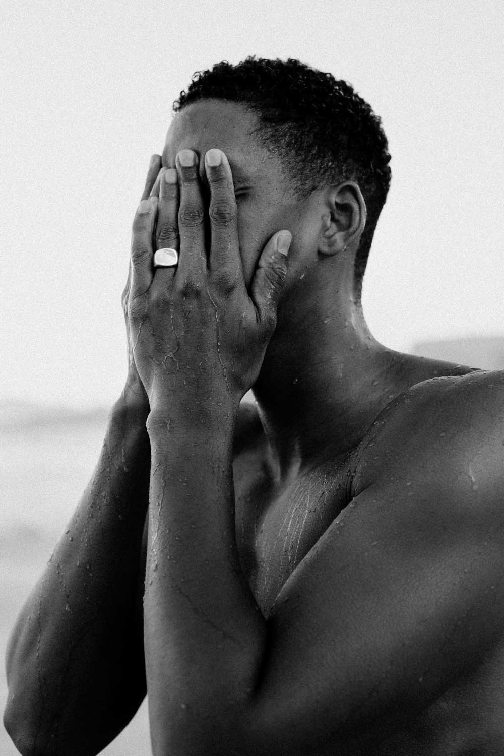 Black and white photo of a person covering their face with their hands