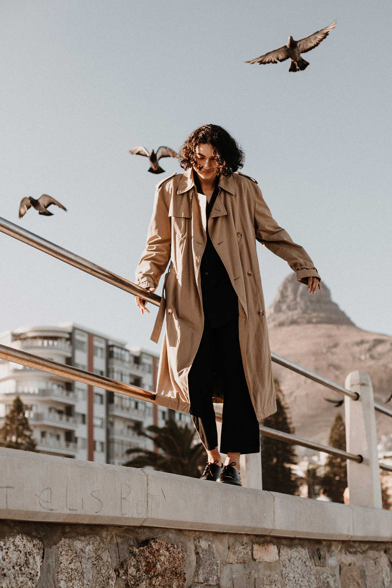Woman in long coat with birds in background