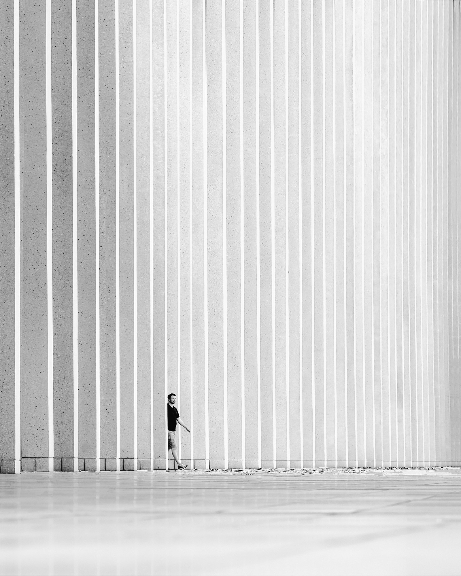 Schwarz-Weiß-Architektur – ganz in Schwarz gekleidete Person im Gehen