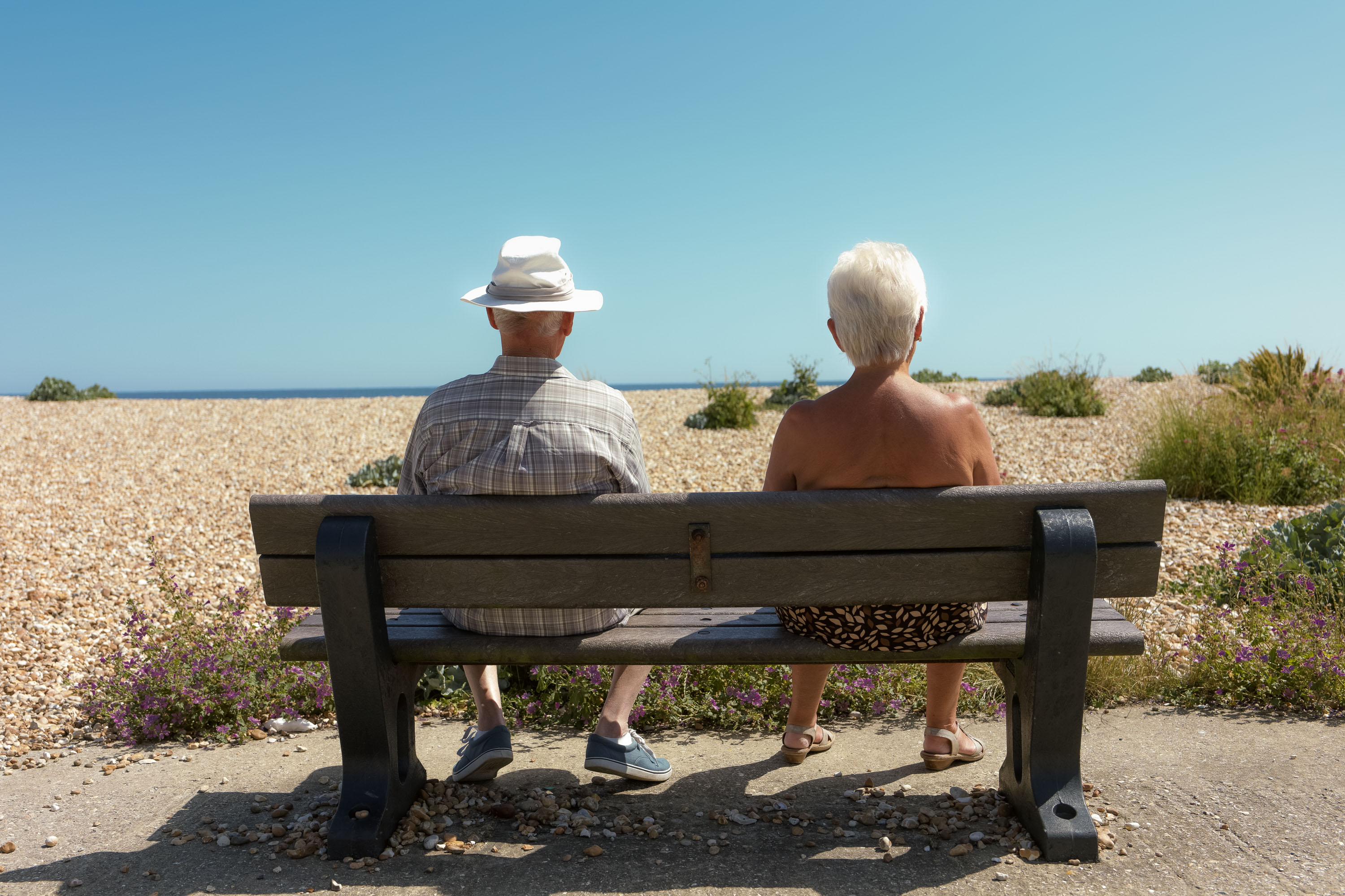 Old couple sitting on a bench on the beach 