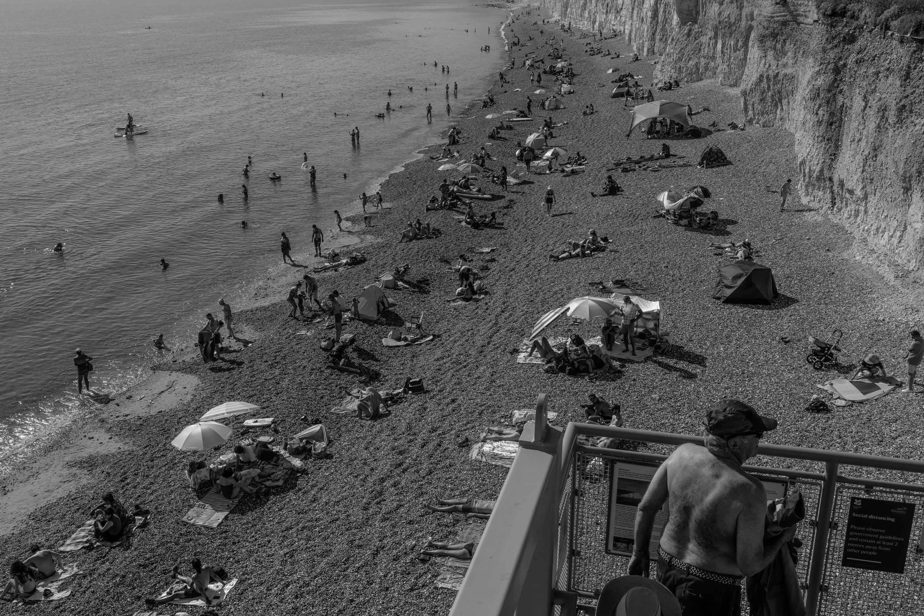 Black and White busy beach next to cliff