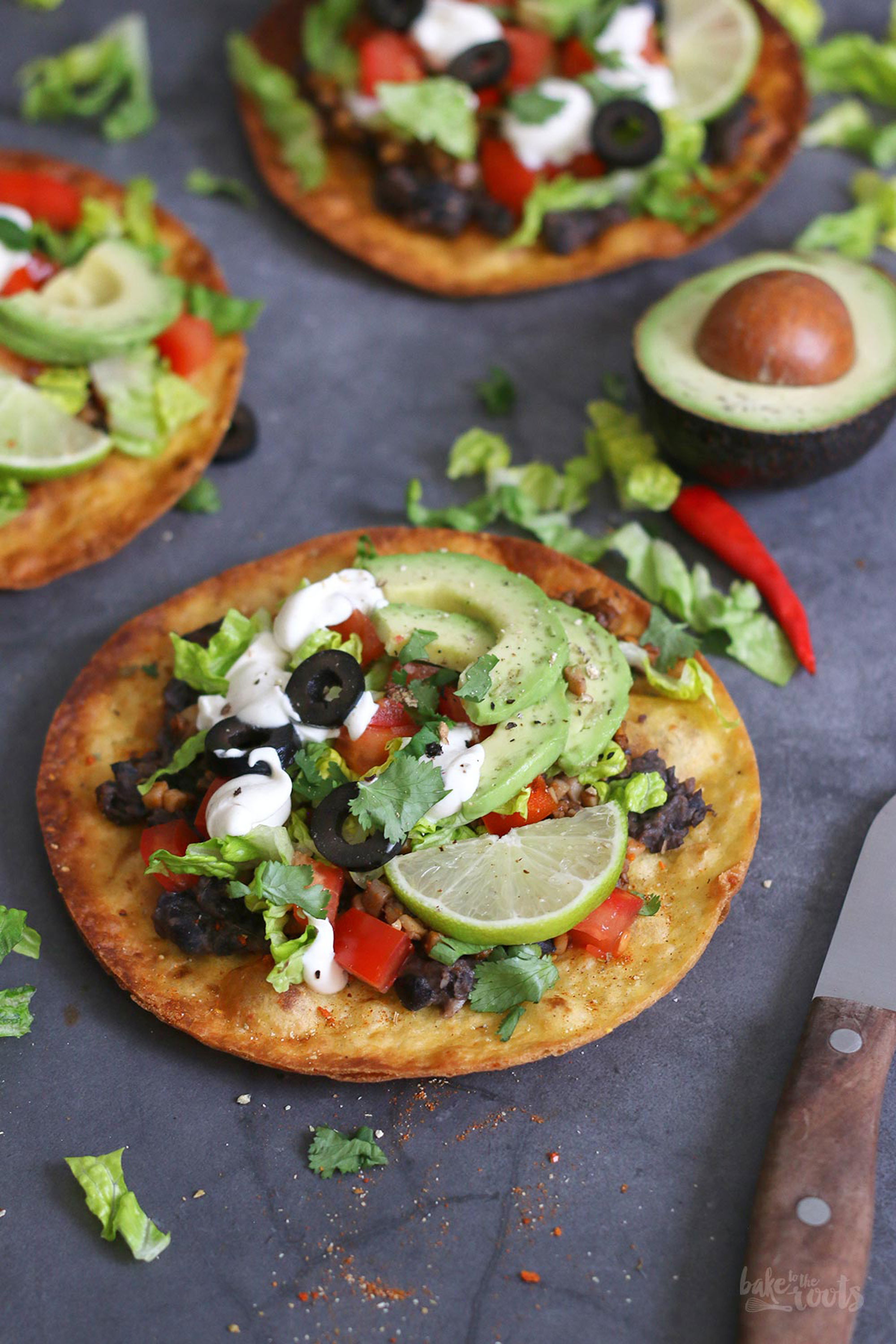 Foto von mit Avocado, Oliven, Tomaten und Limetten belegten Teigfladen
