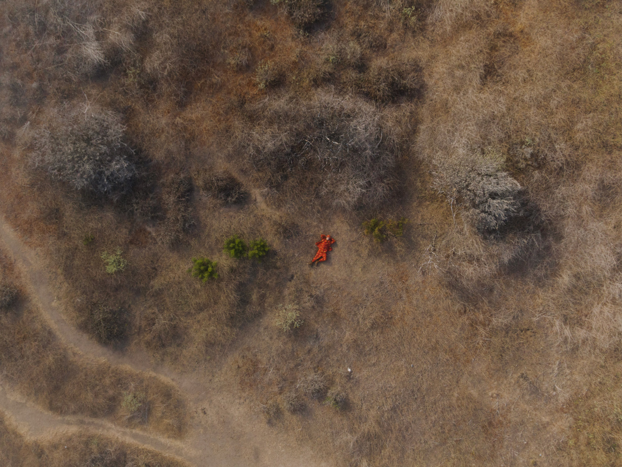Aerial drone shot of person laying down in an arid environment 
