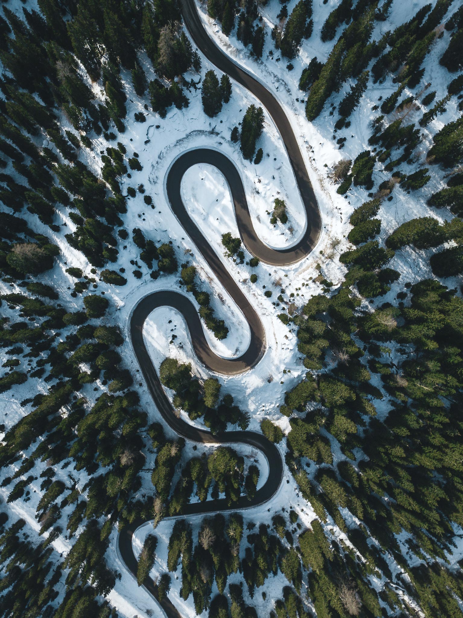 Aerial image of a winding road through forest and snow
