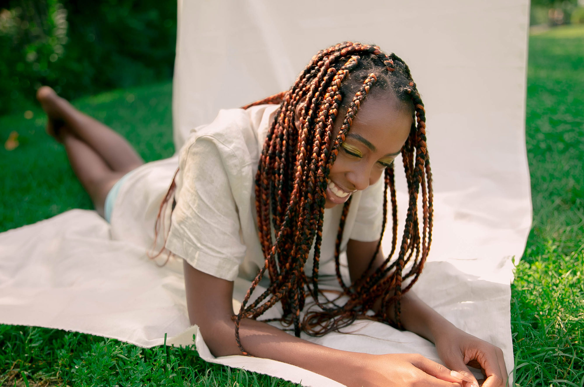 Person lying down on a white sheet that is on the green grass