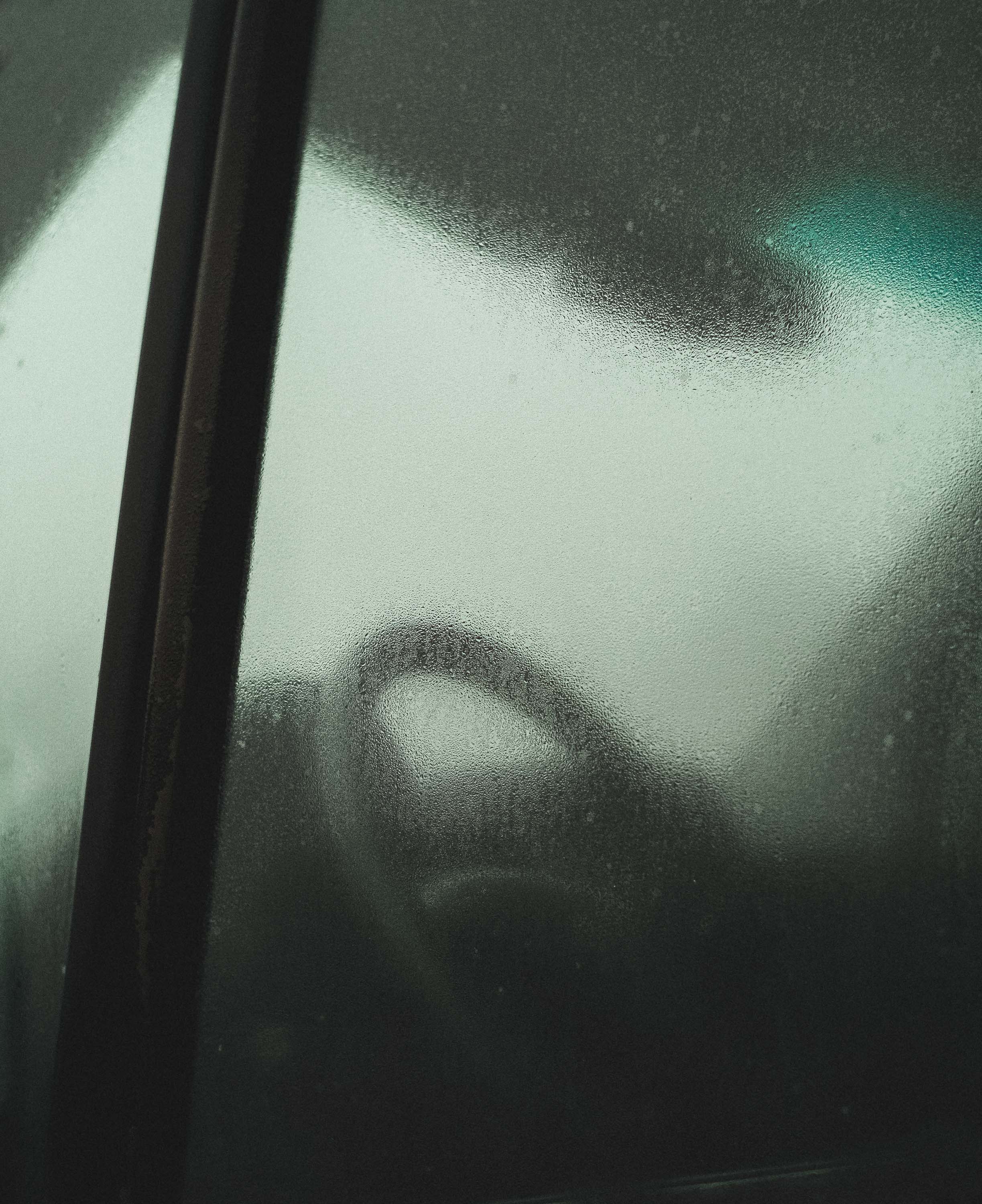 Car driving wheel through a misty, rainy window