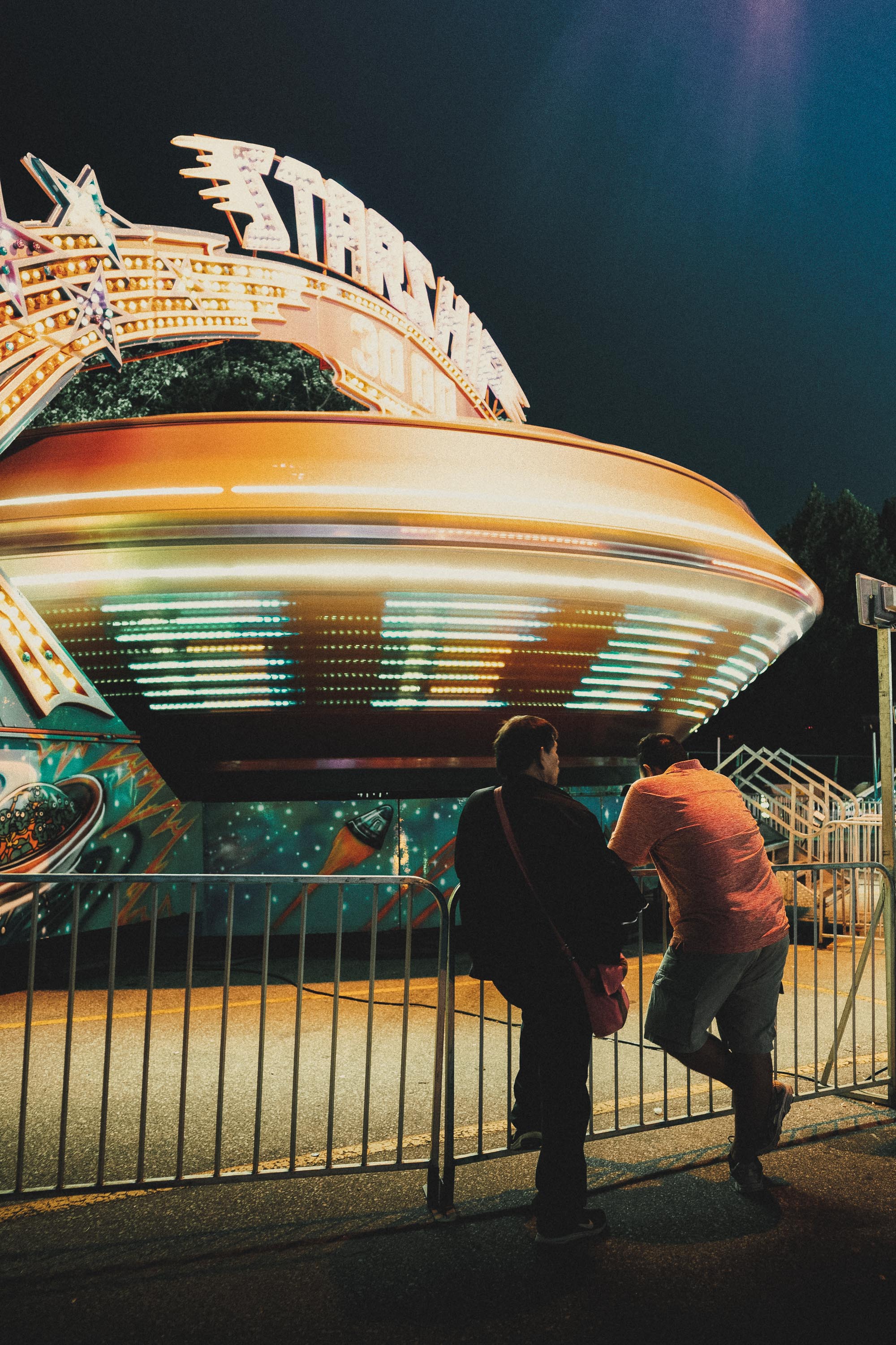 Fairground ride in blurred motion as two people watch on
