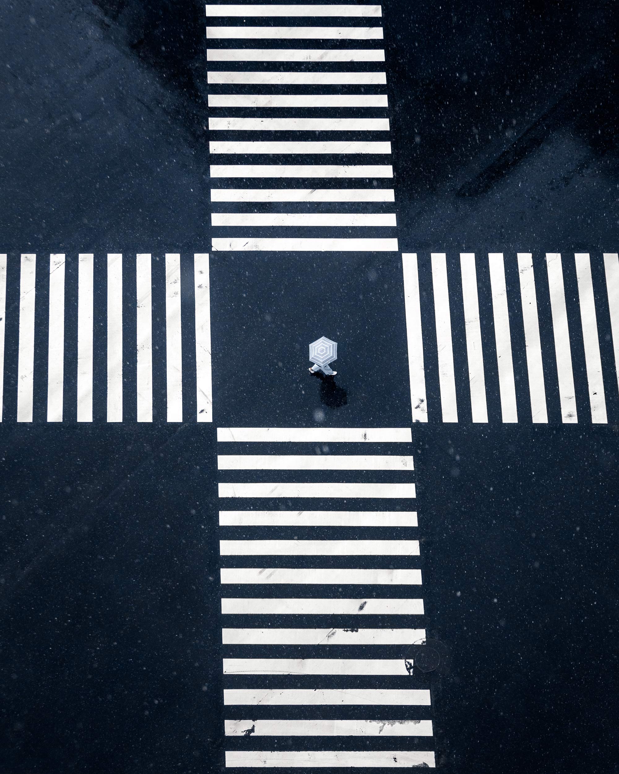 A picture taken from above of an intersection that a person is crossing.