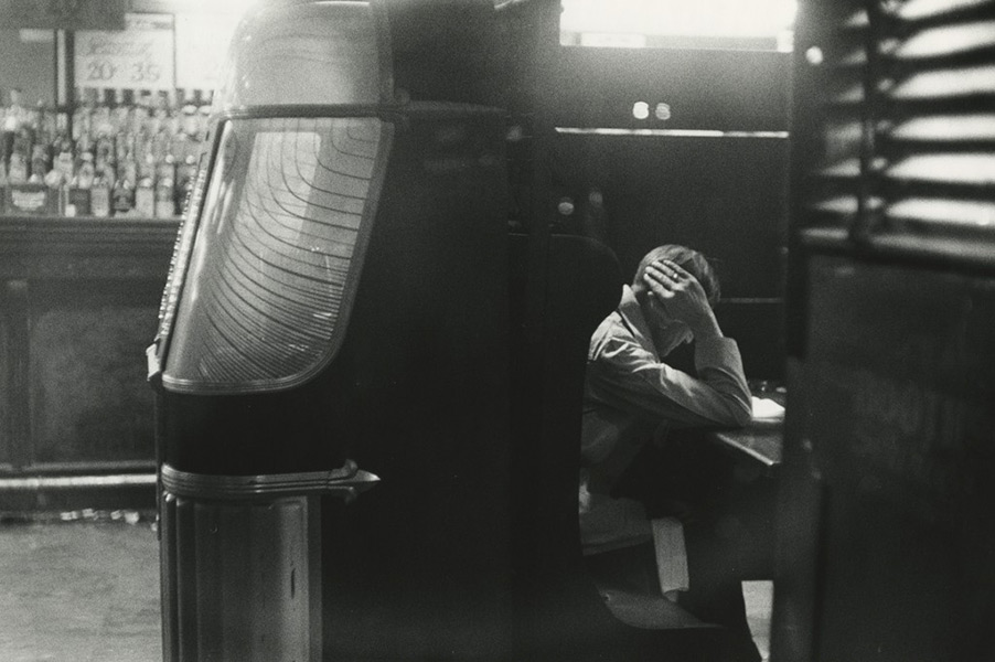 Black and white picture of a man reading a book in a bar