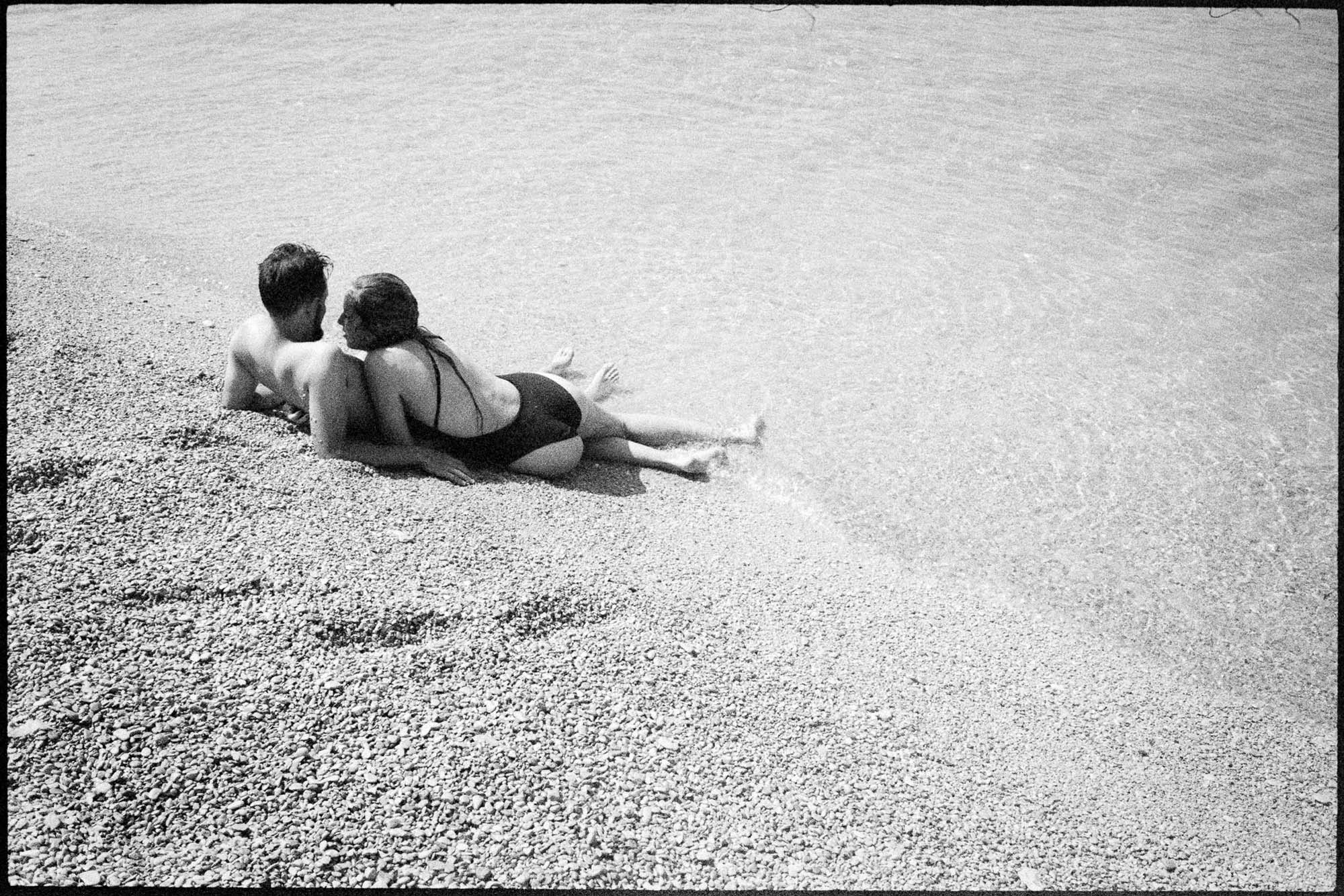 A picture of two people lying on the beach