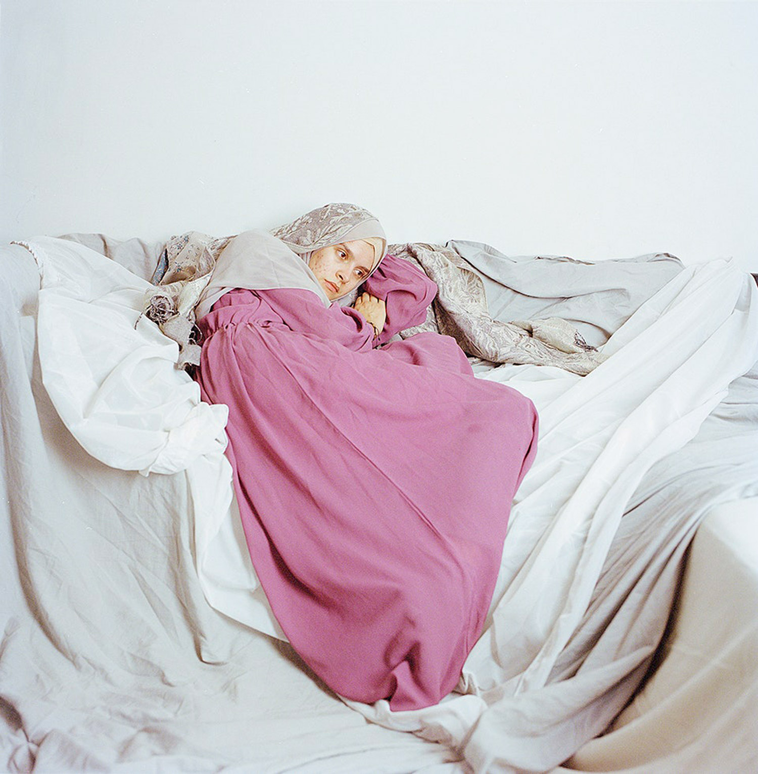 Woman lying down amongst lots of sheets. Jodie Bateman @jodiembateman.