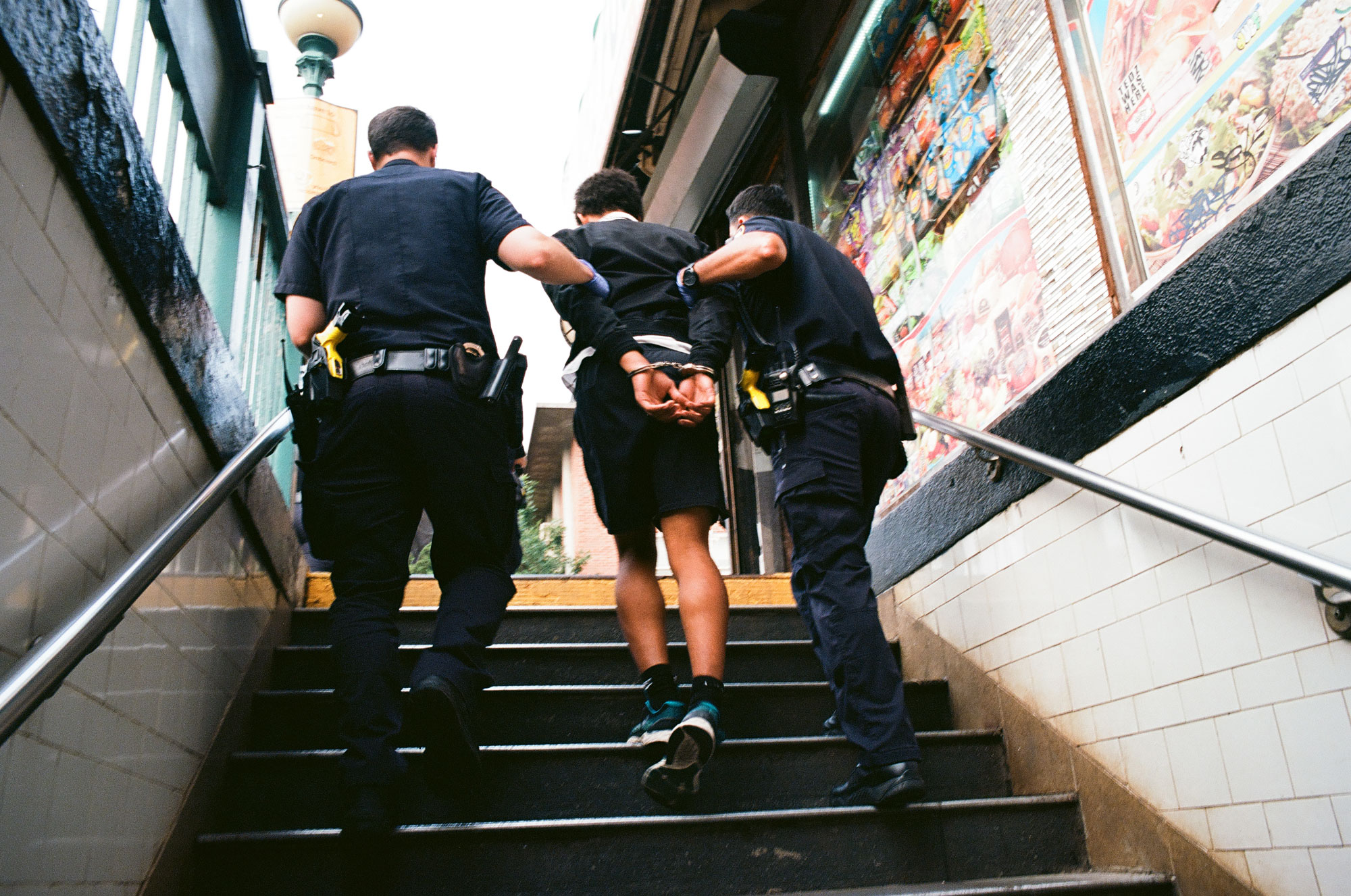 A person being arrested by two police officers, whilst walking upstairs