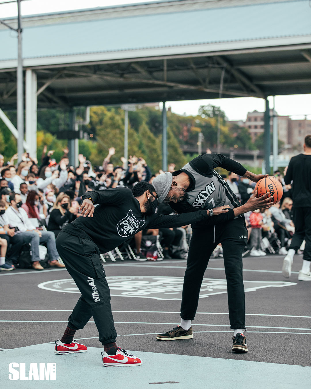 Twee basketbalspelers duelleren terwijl een menigte toekijkt