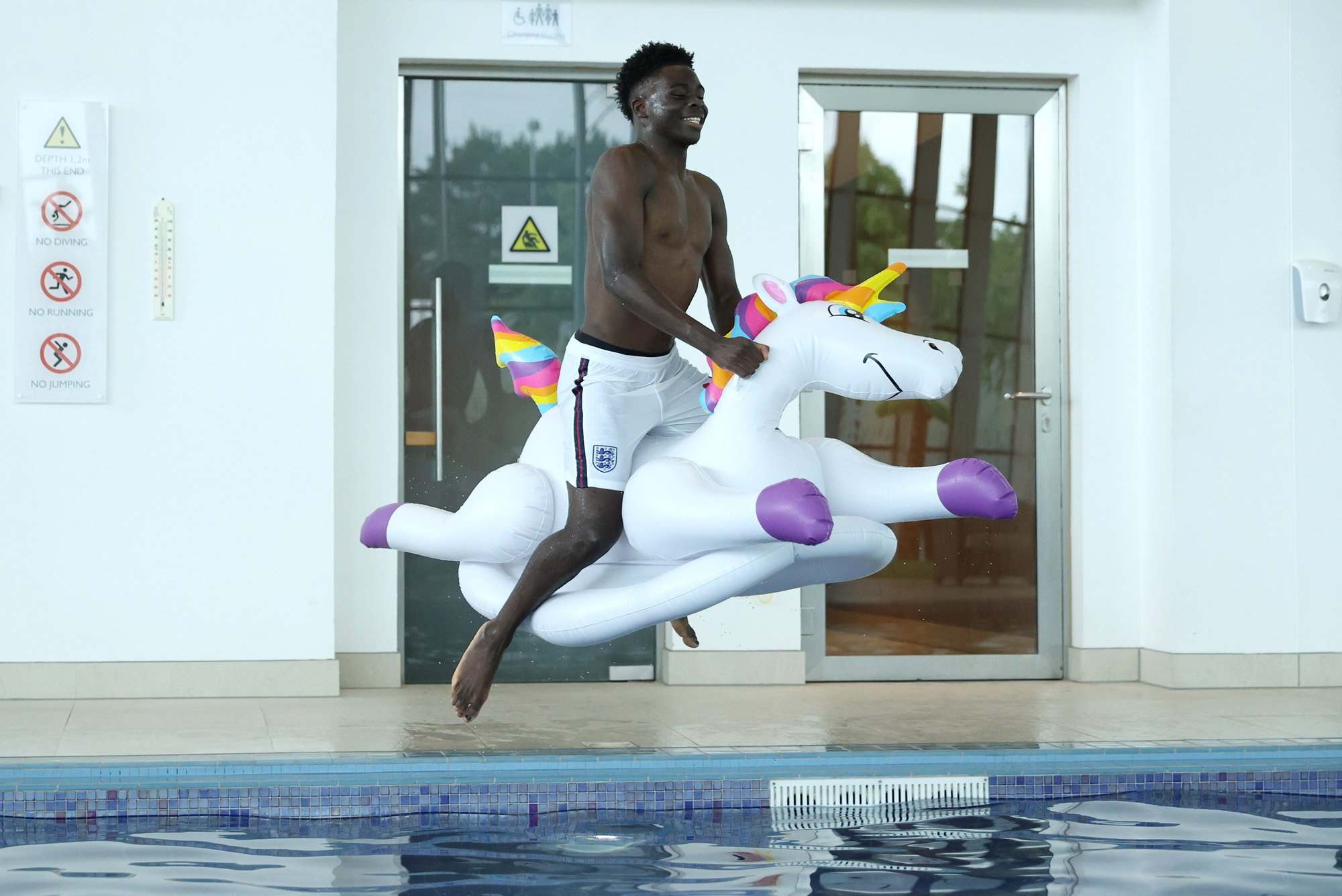 Bukayo Saka on a blow up unicorn in a swimming pool