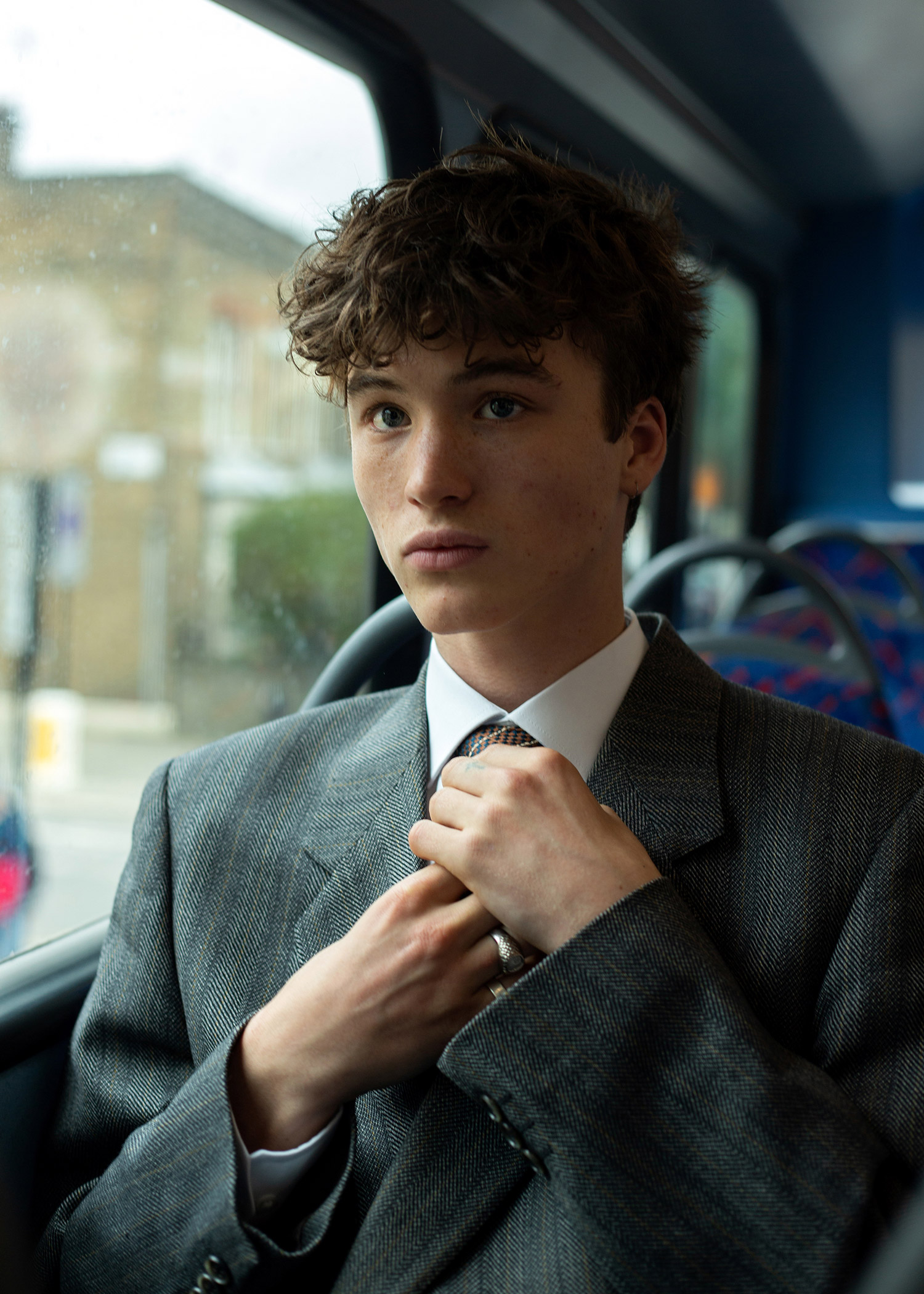 Boy on the bus in school uniform adjusting his tie 