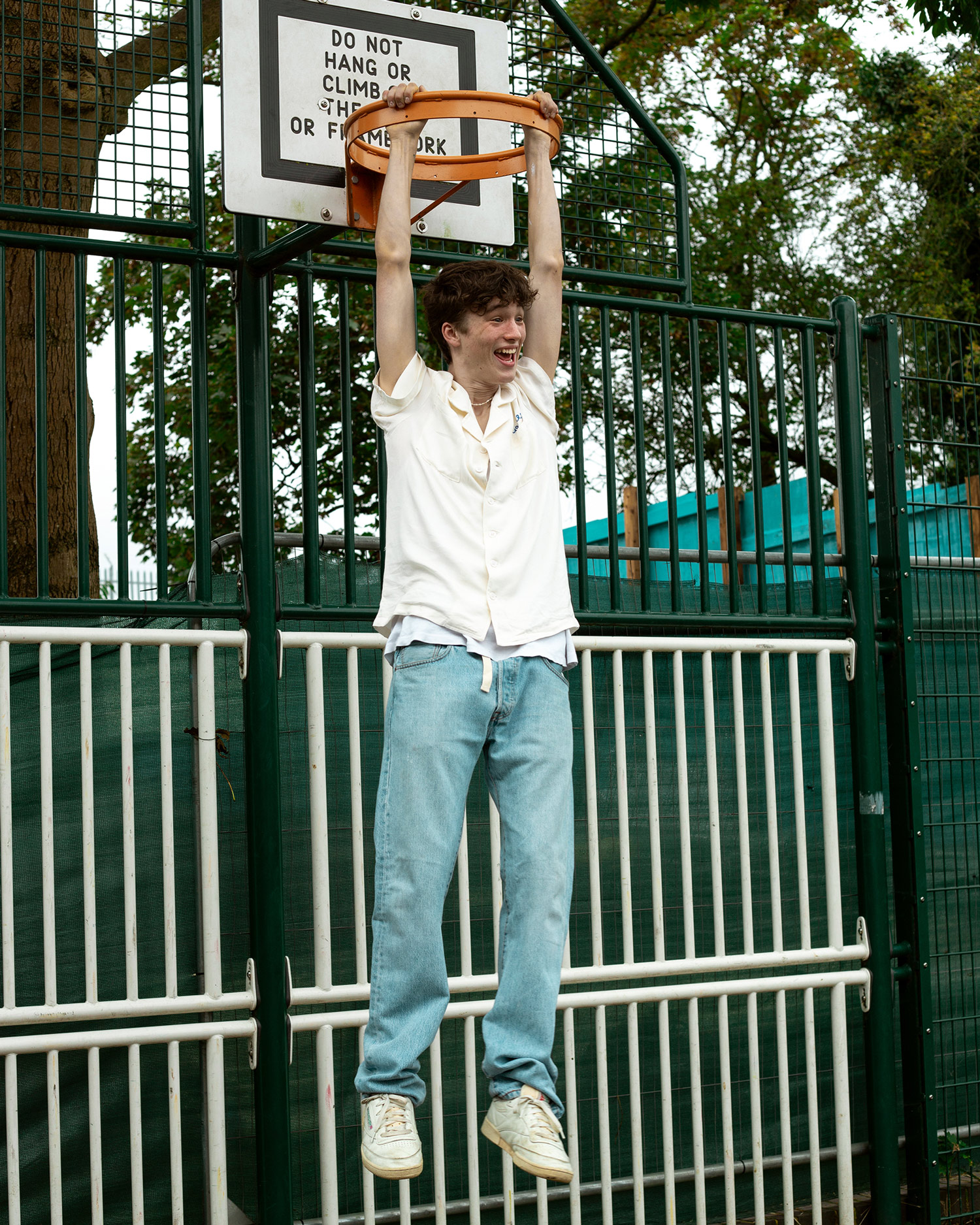 Boy hanging from a basketball hoop