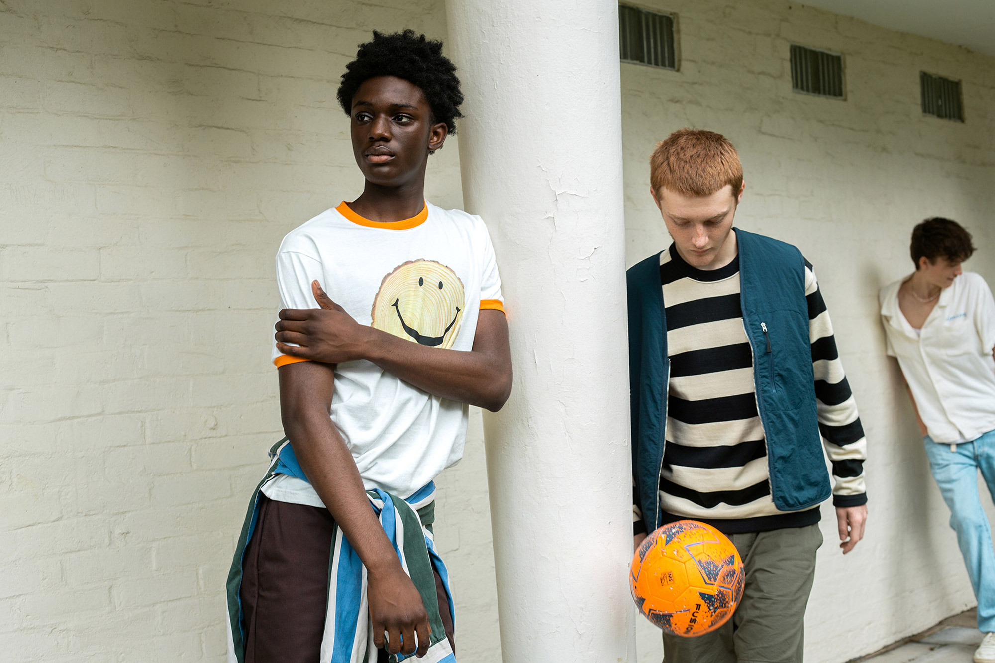 Two people leaning against a concrete pillar 