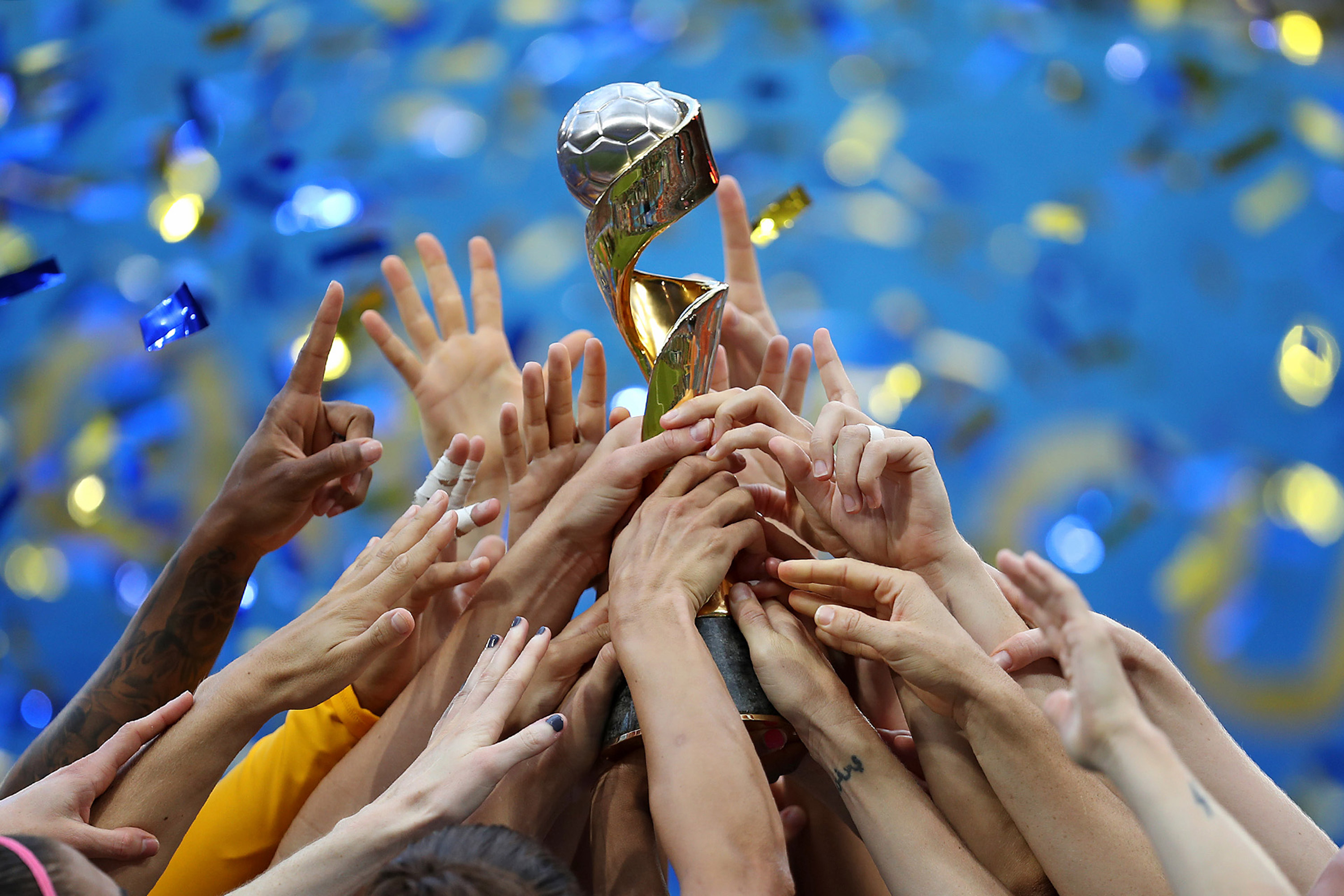 De handen van voetballers houden samen een trofee omhoog 