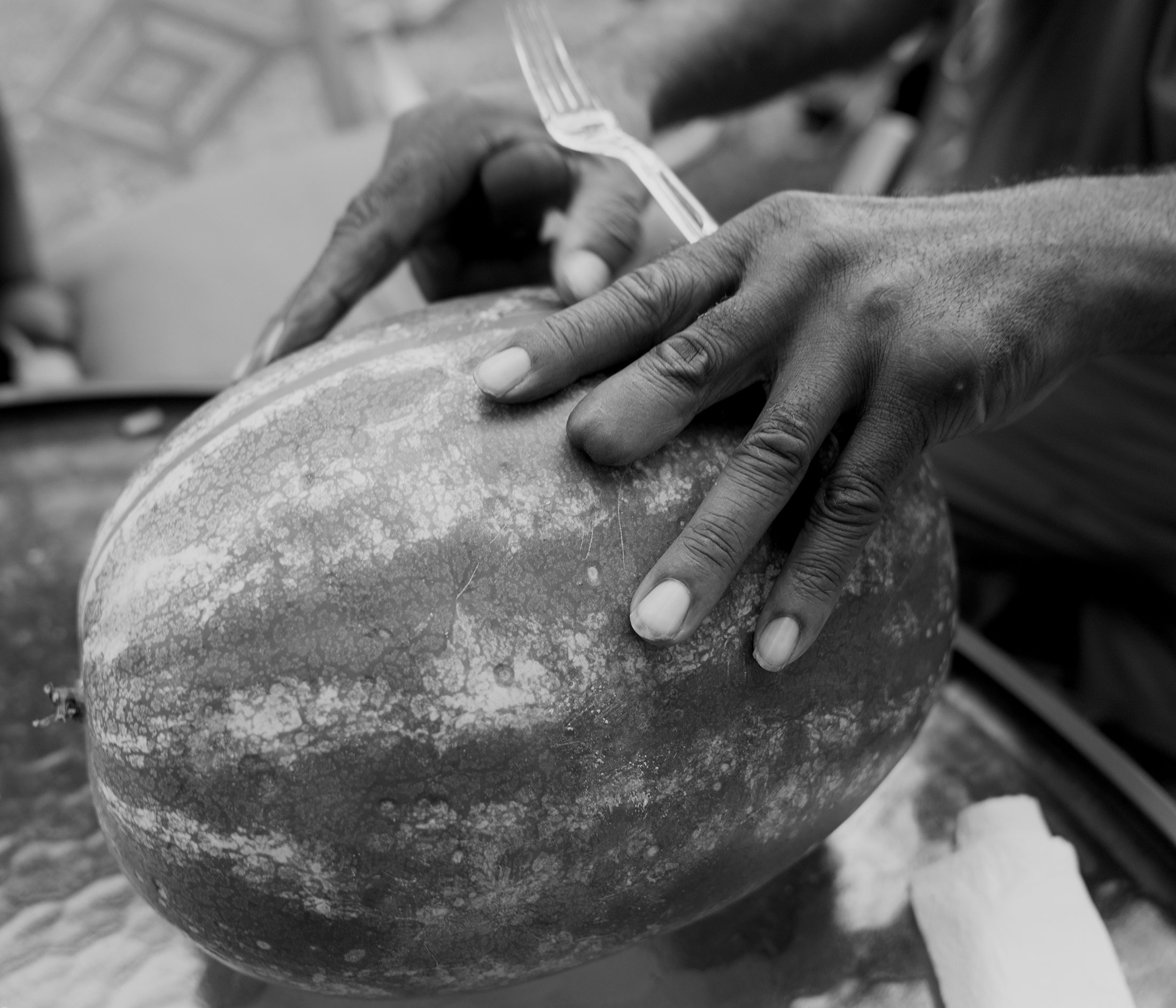 Hands on a melon with one fingertip missing