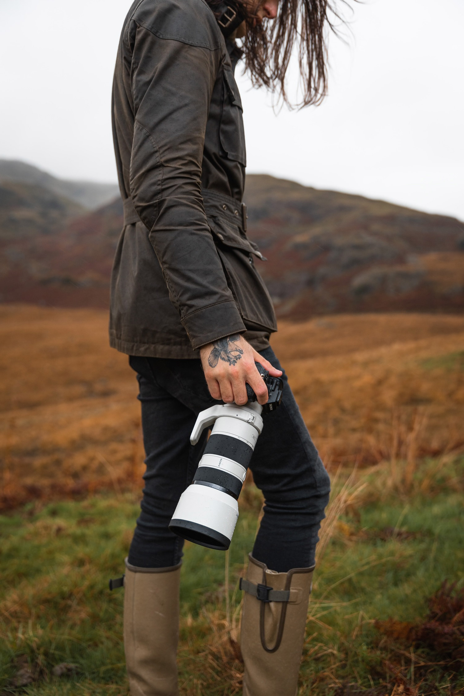 a photographer walking up a hill with a long lens fitted. 