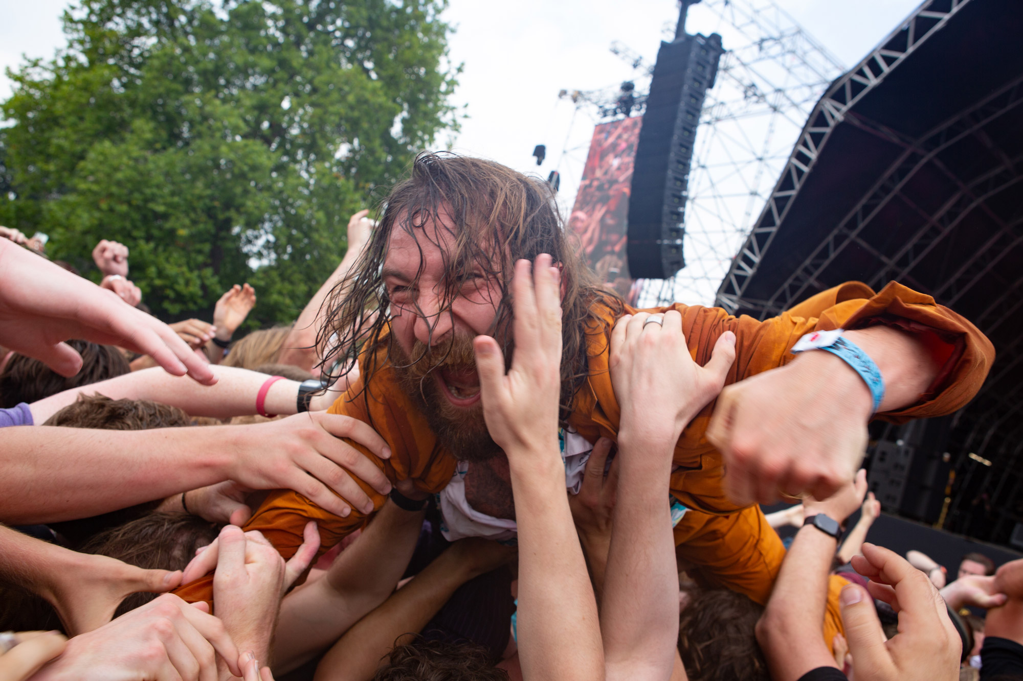 a man with long wet hair crowd surfing at a festival