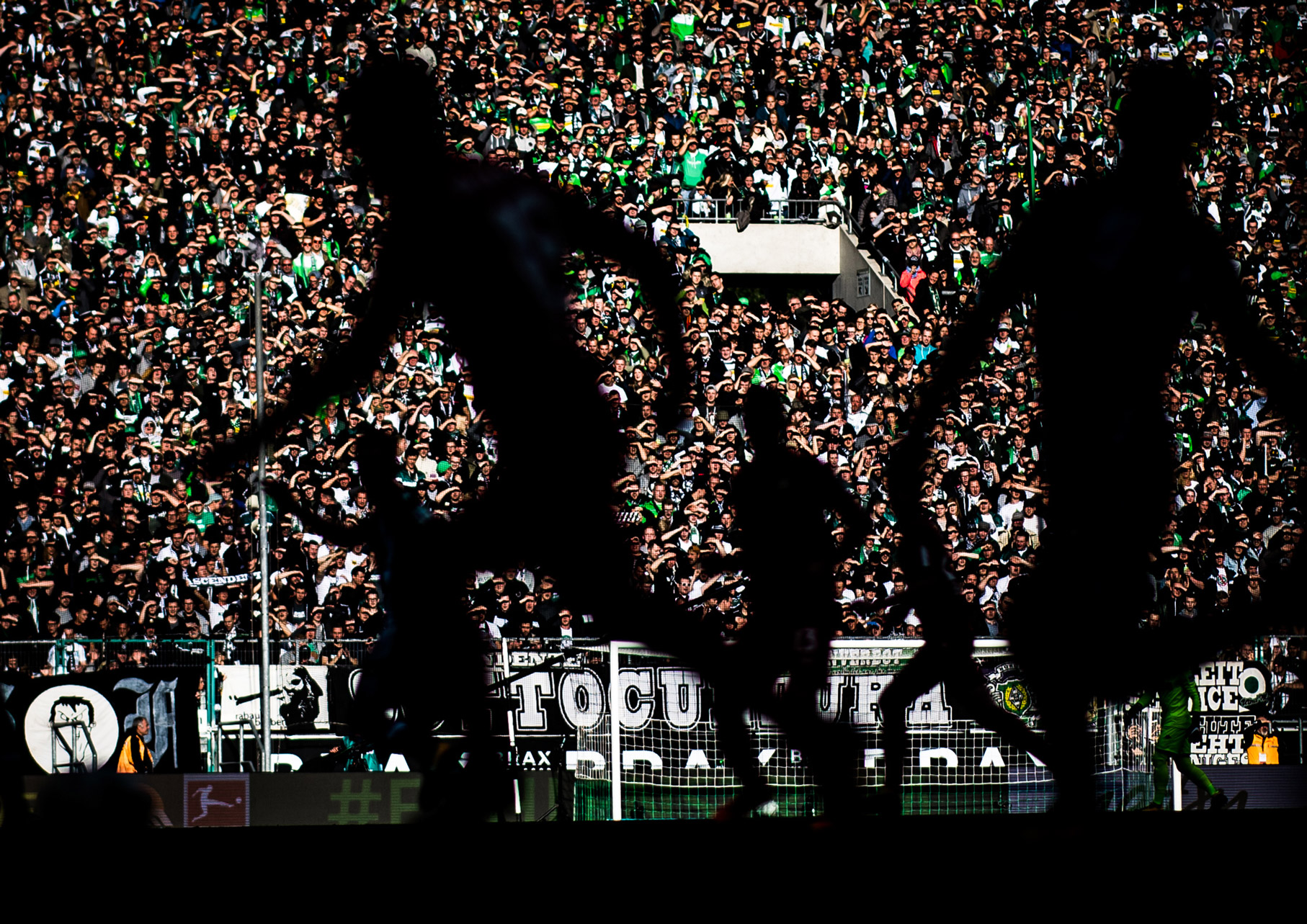 Een foto van een publiek tijdens een voetbalwedstrijd. De voetballers zijn in het midden onscherp.