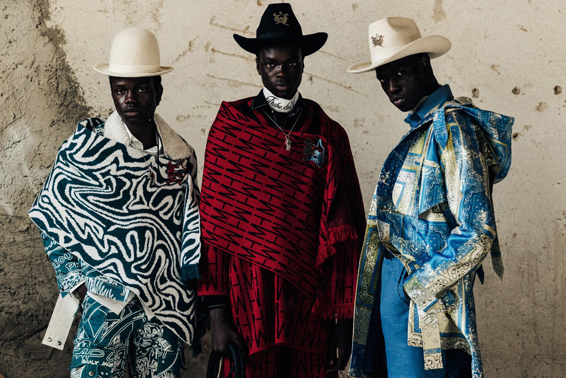 Three people wearing cowboy outfits posing for a camera