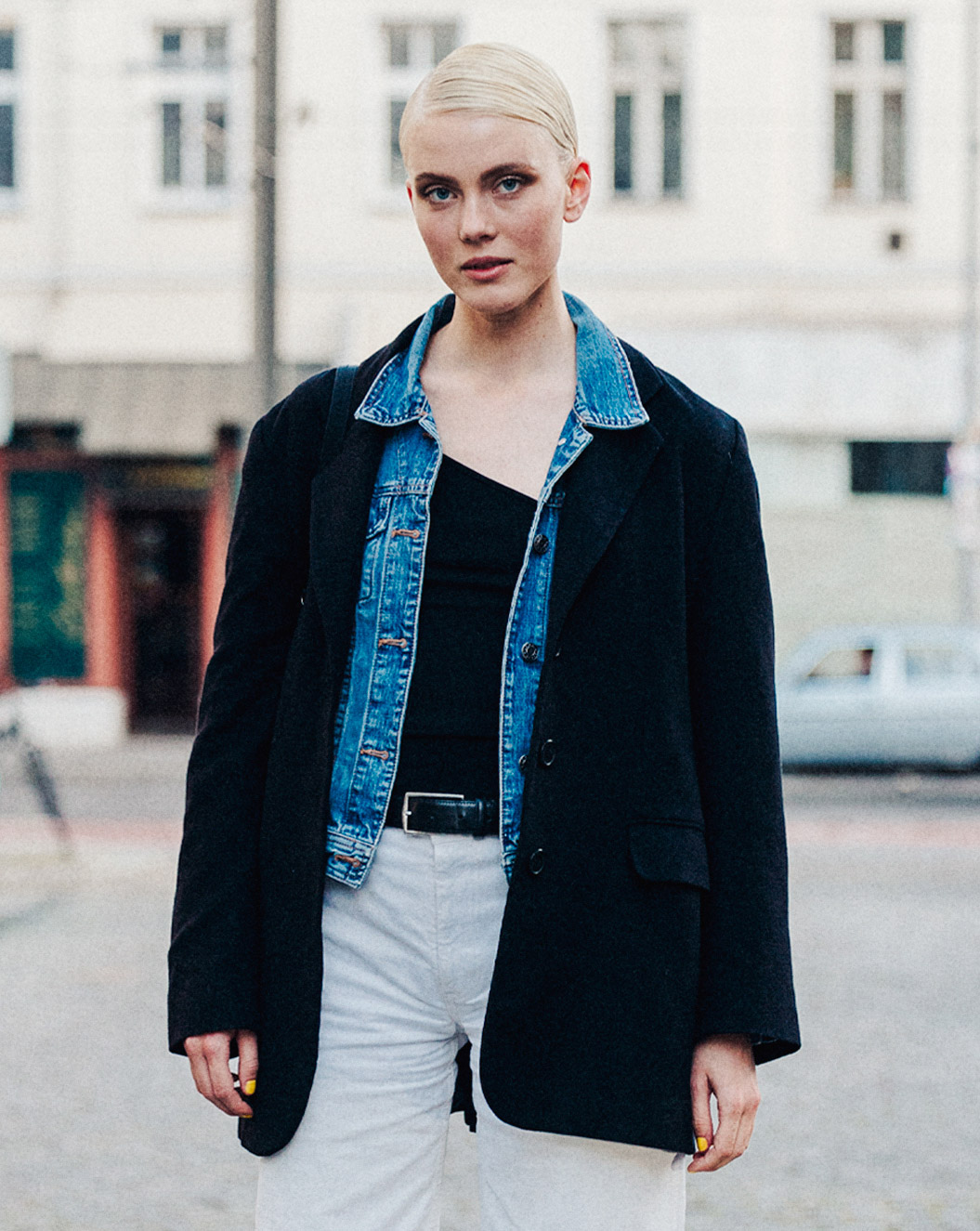 eine Dame mit kurzen blonden Haaren, in einer Stadt, die für eine Kamera posiert