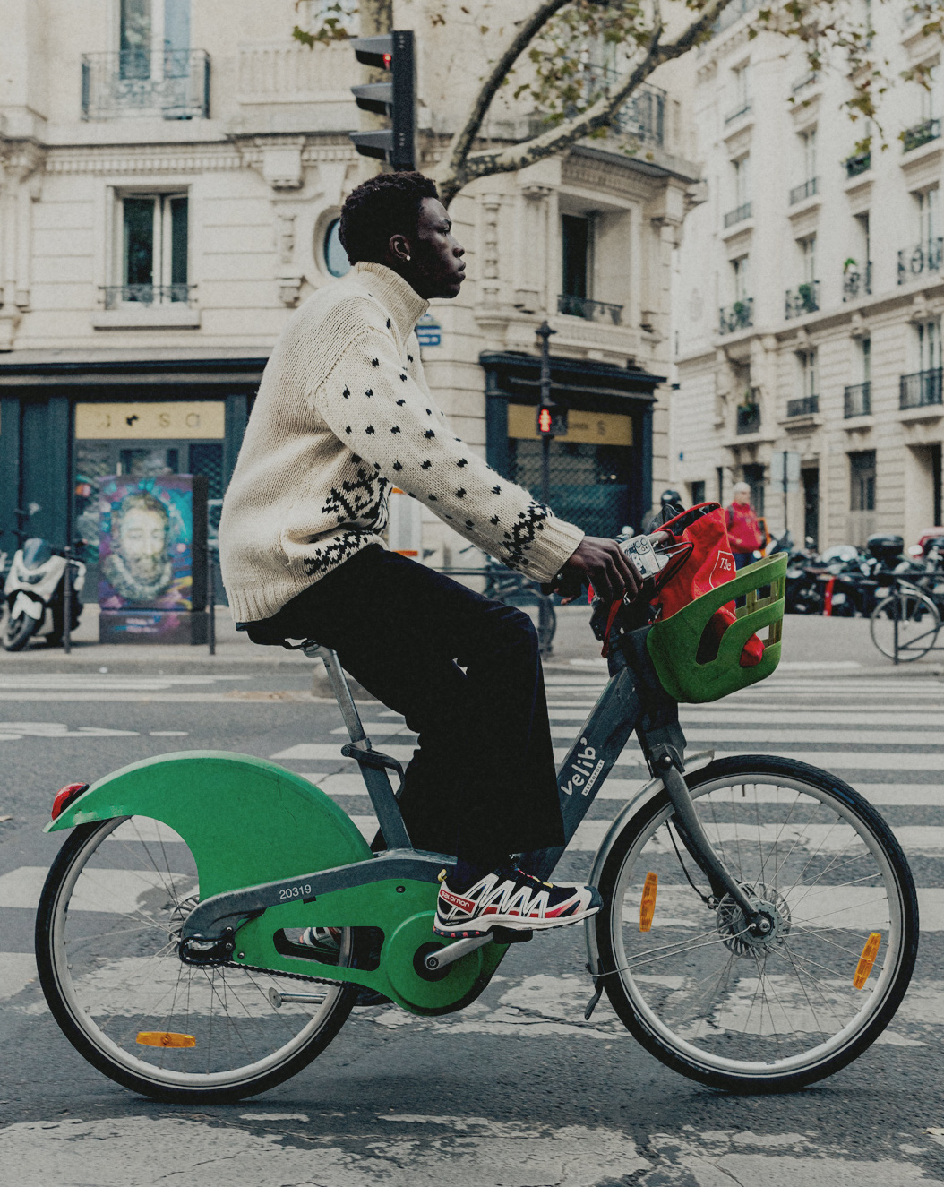 Een persoon rijdt op een groene stadsfiets, draagt een witte trui en een zwarte spijkerbroek