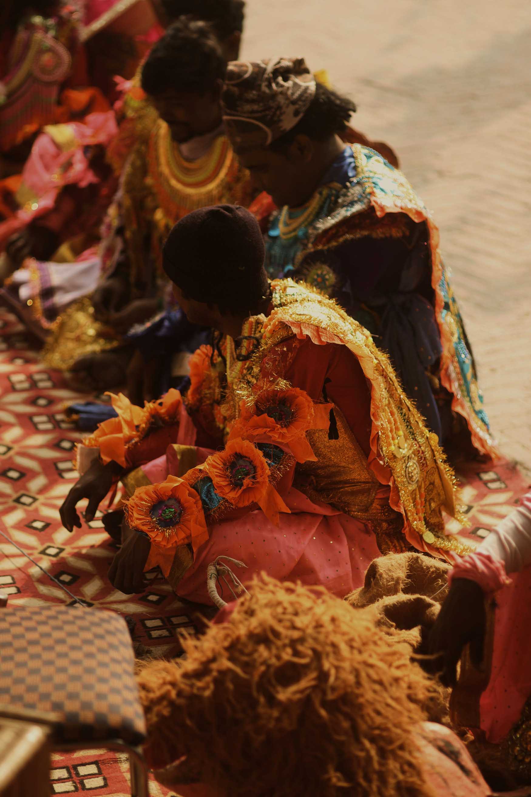 A group of people sitting down in a row wearing traditional clothing
