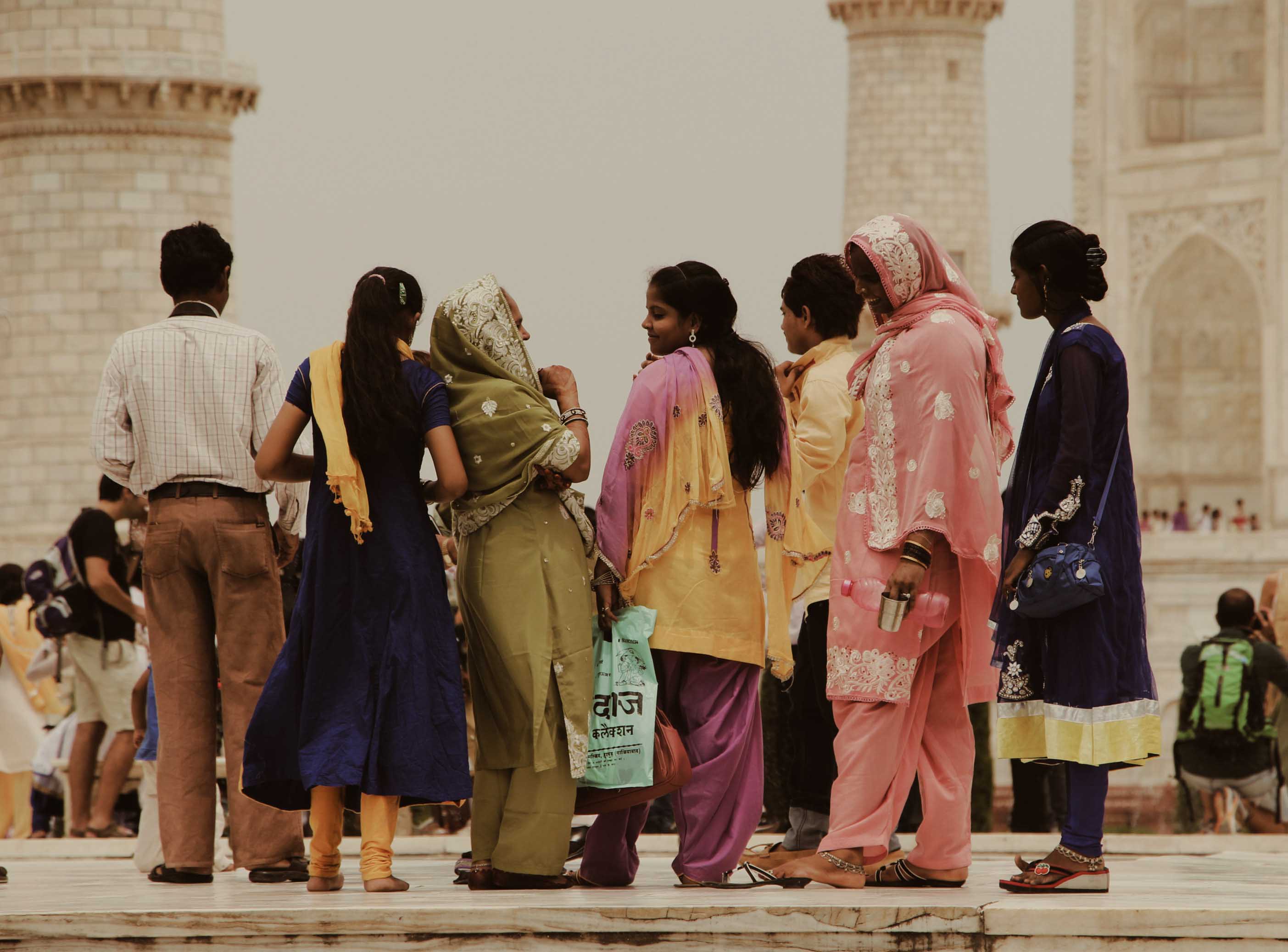 A group of people, some wearing traditional clothing, looking at the Taj Mahal