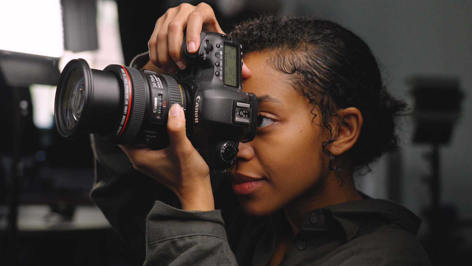A photographer wearing a black shirt in a studio shoots a portrait using a Canon EOS 5D Mark III