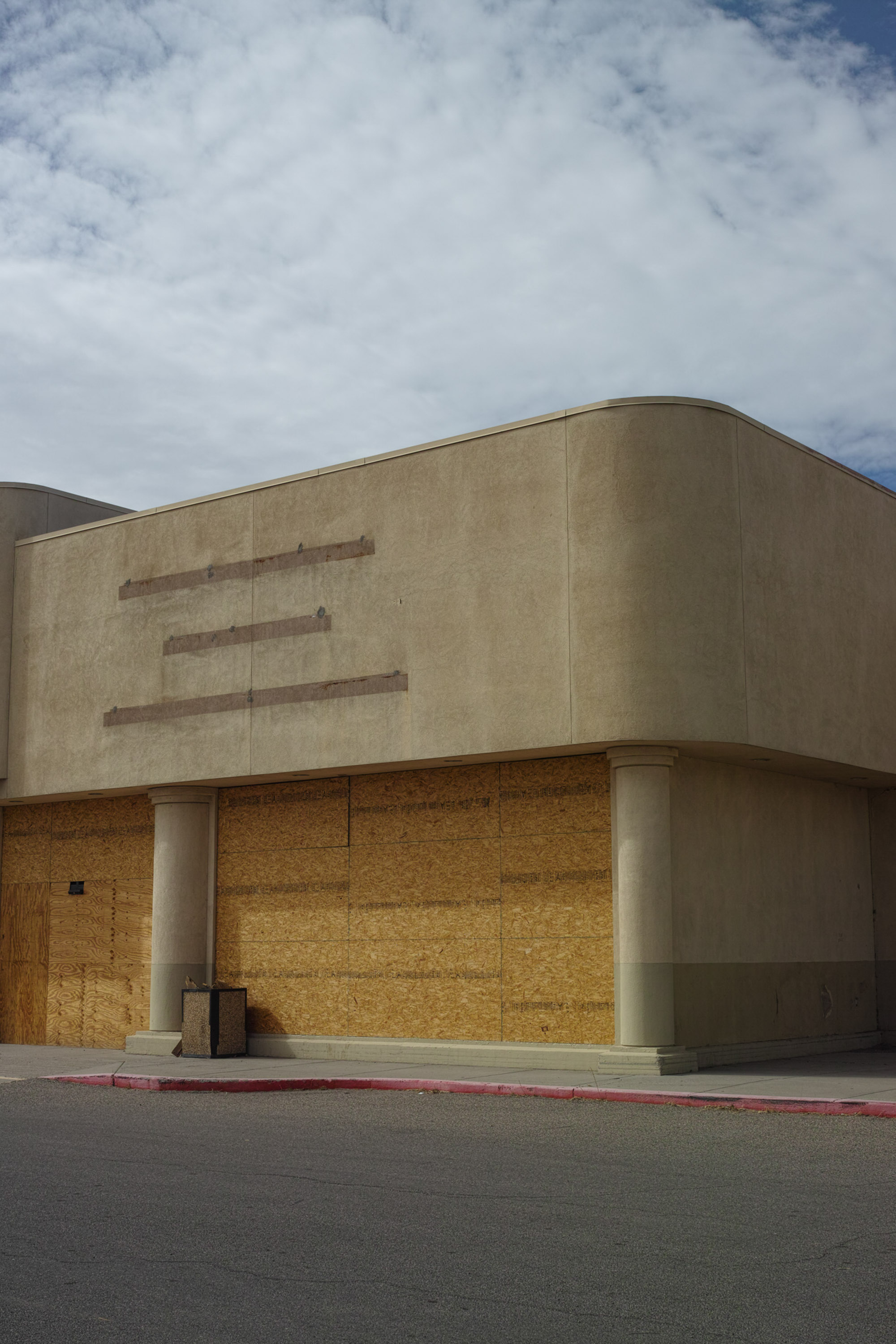 A grey building on a street corner with a cloudy blue sky in the background