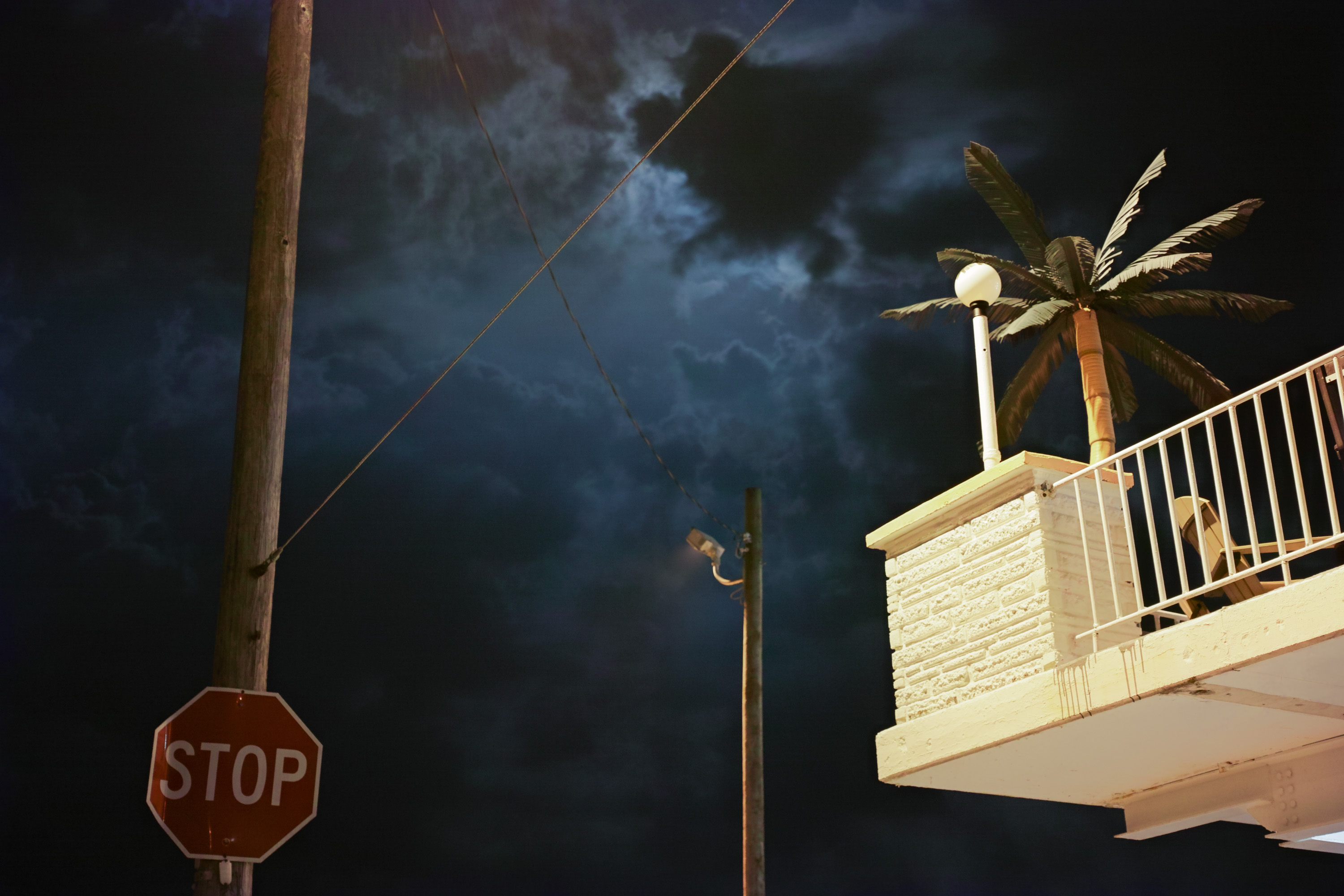 The sky at night with a balcony and a stop sign on either side of the frame 