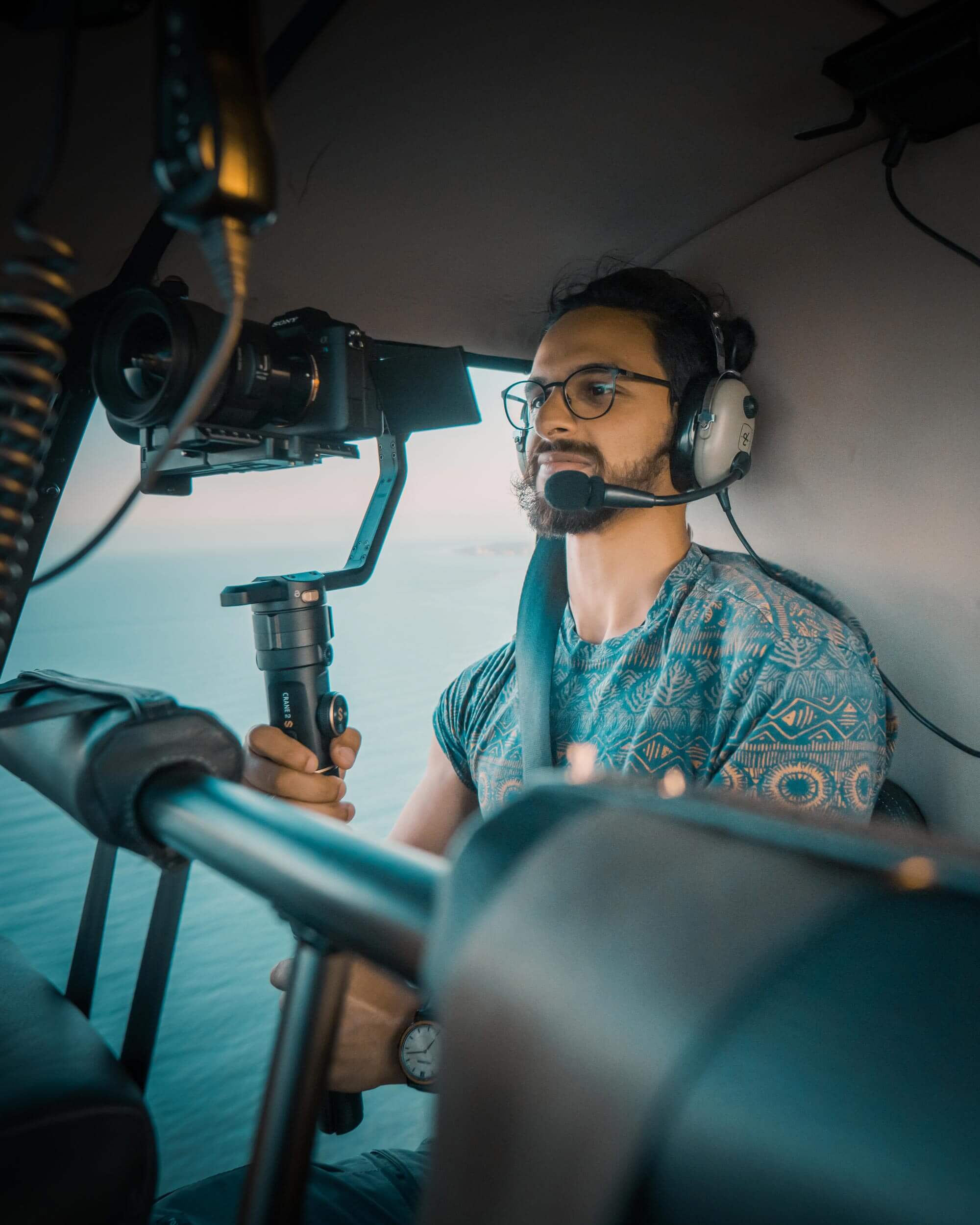 A photographer in a helicopter holding his camera on a gimbal
