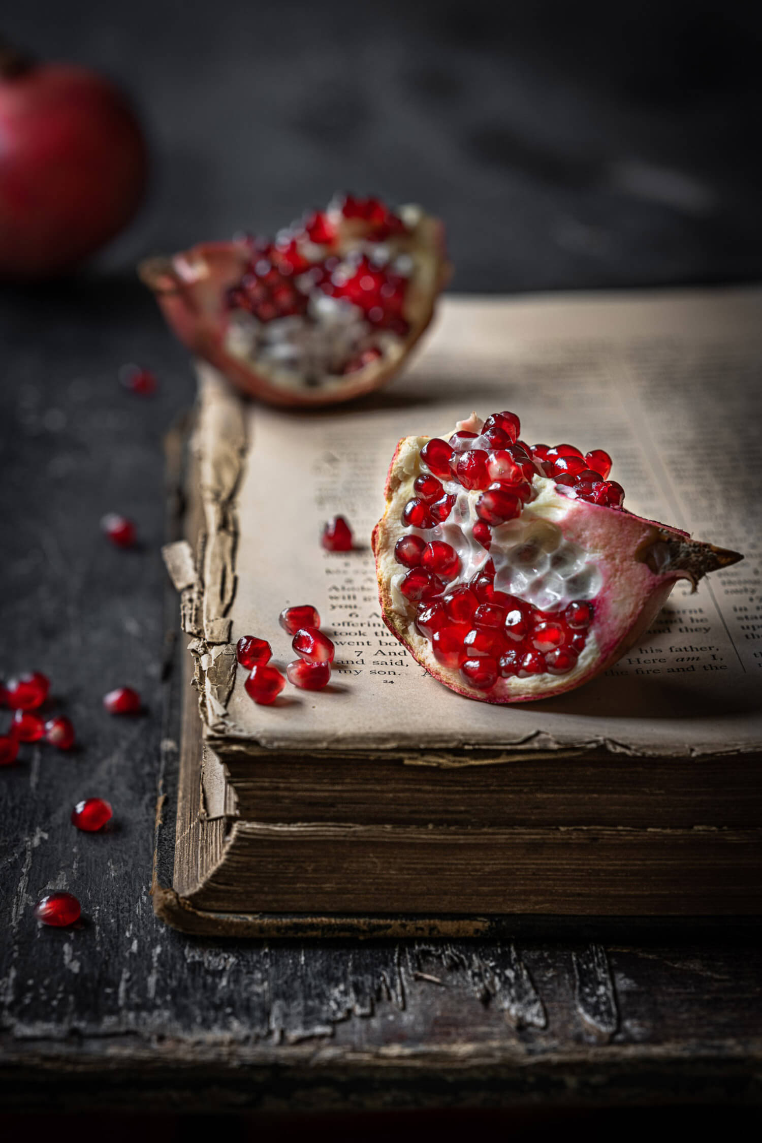 a sliced pomegranate on top of pages of an open book
