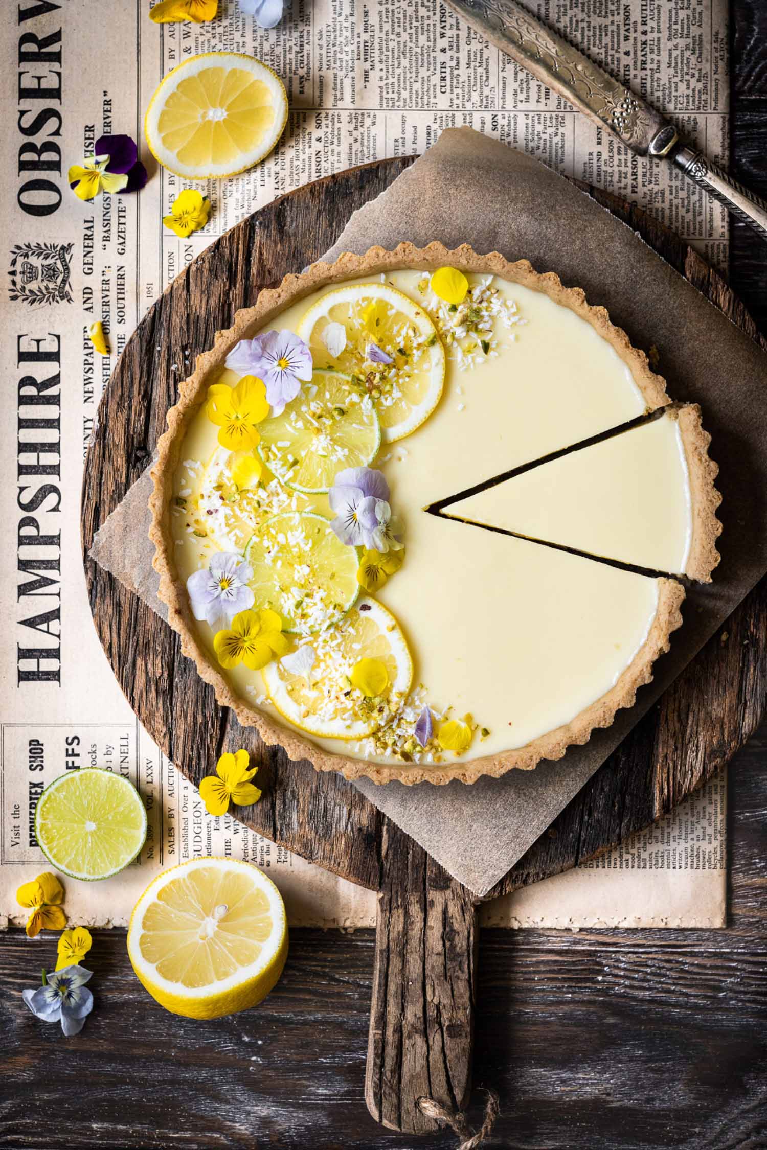 a lemon tart with lemons and purple flowers on top