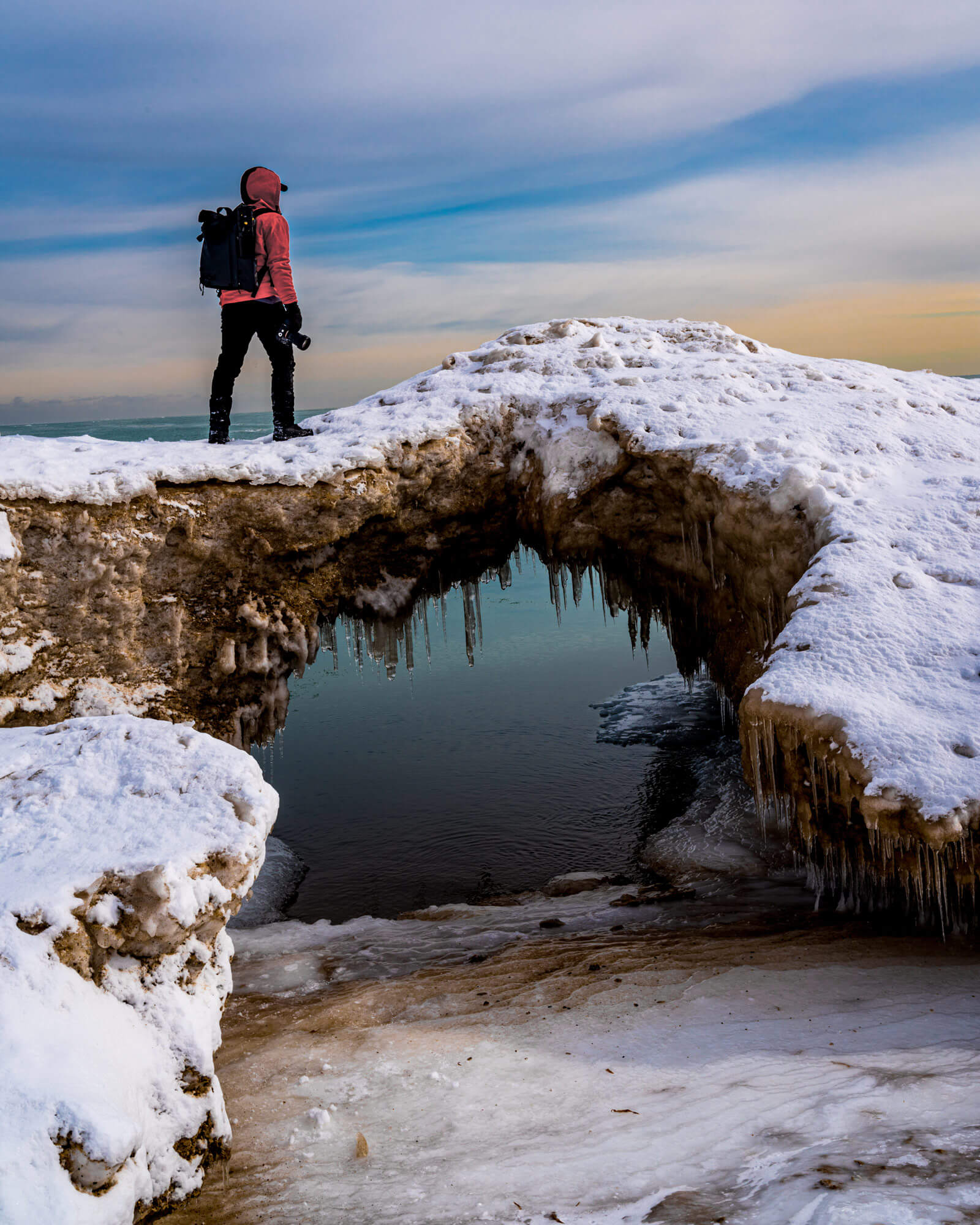 A person walking in the snow over an old bridge