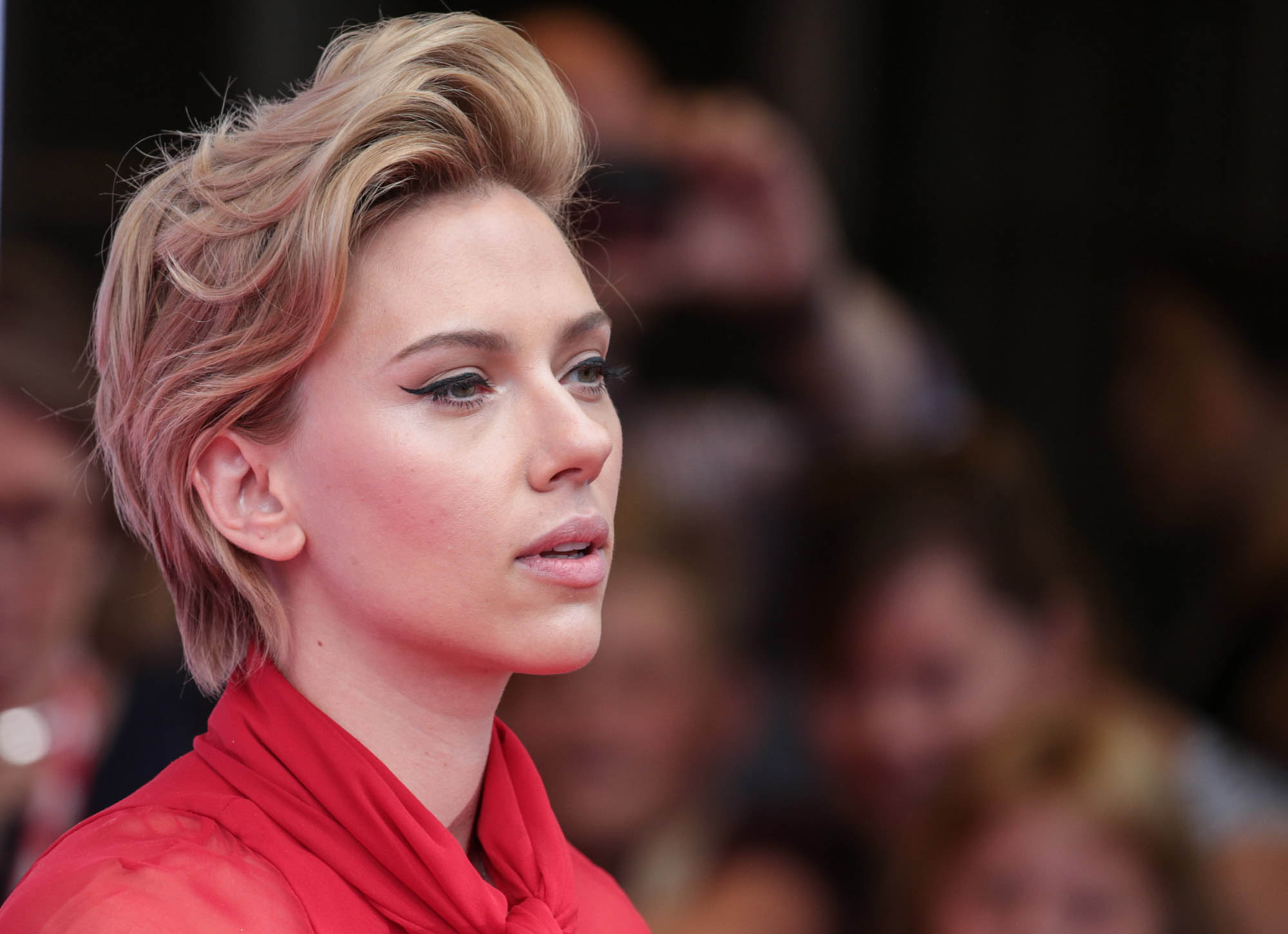 Scarlett Johansson wearing a red dress with photographers in the background.