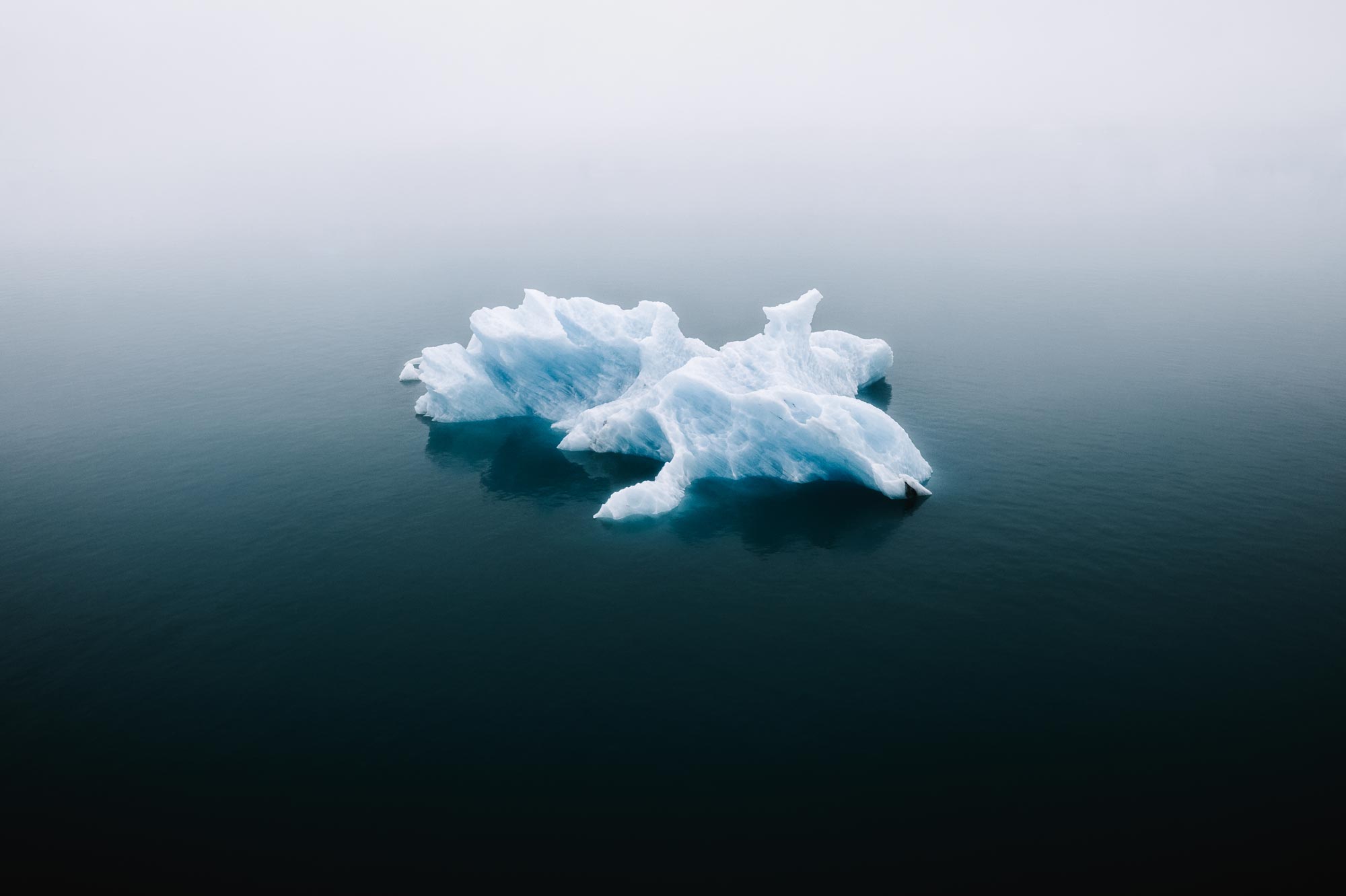 A drone picture of a small iceberg in the middle of the ocean