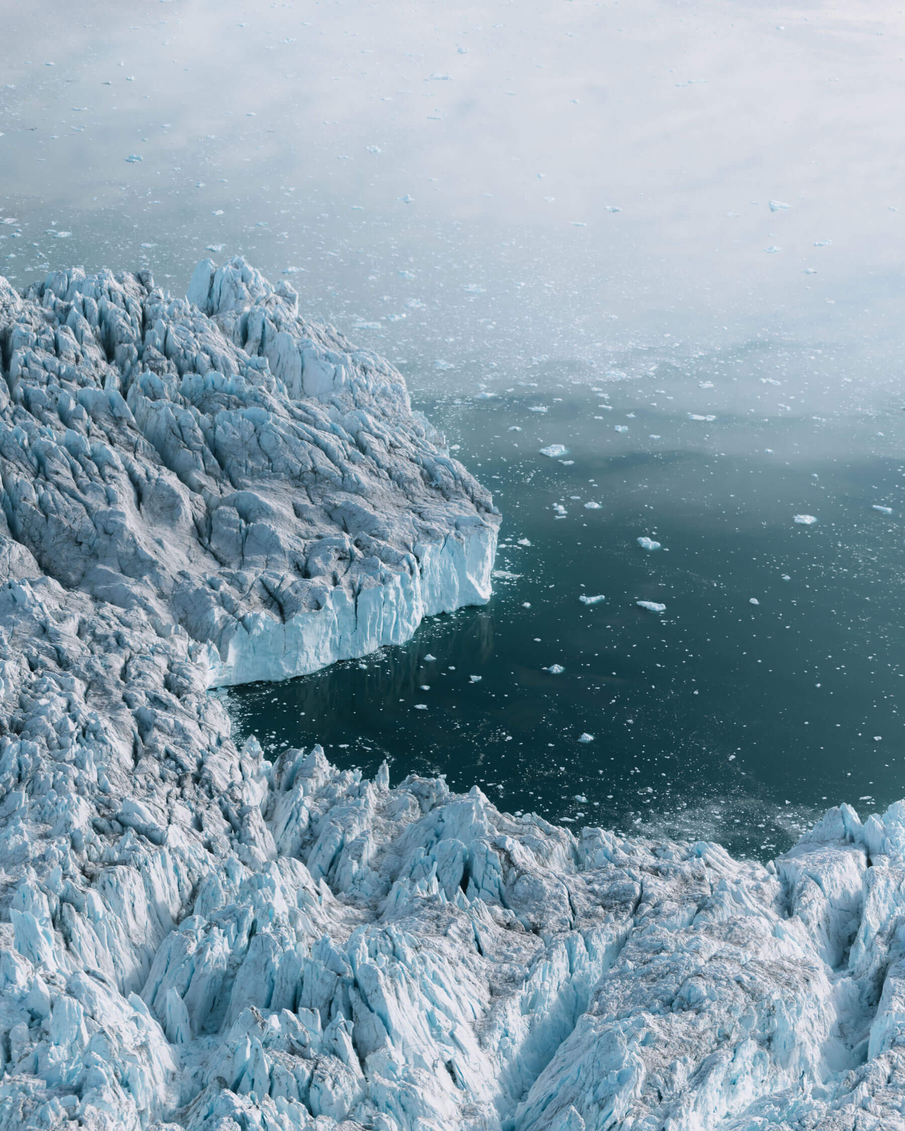 Ein Ausblick von einer gefrorenen, verschneiten Gebirgslandschaft neben dem Meer
