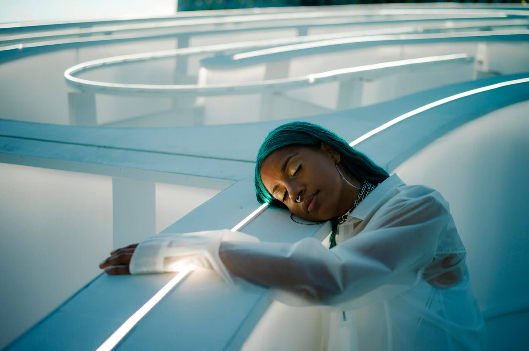 Lady with green hair resting head on a pillar eyes closed