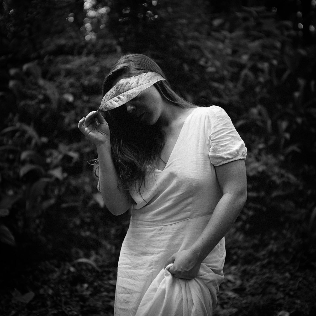 A woman with a leaf cascading over her face.