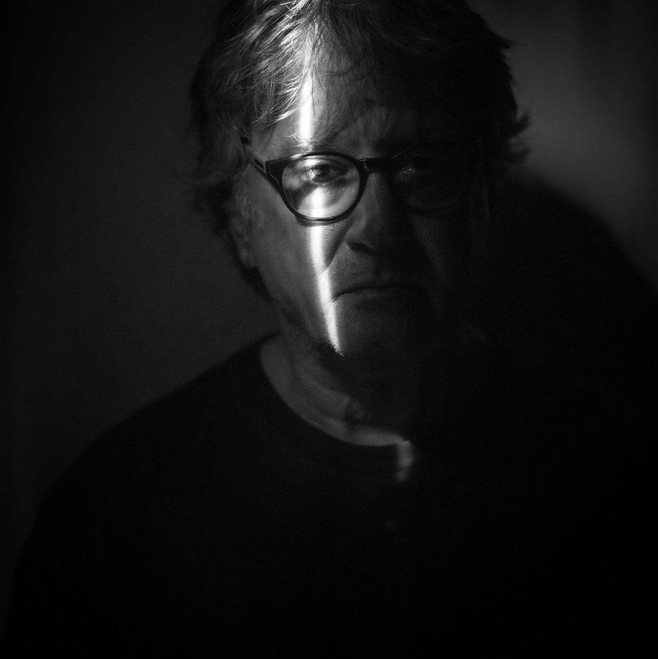 A man with a single shred of light illuminating his face.